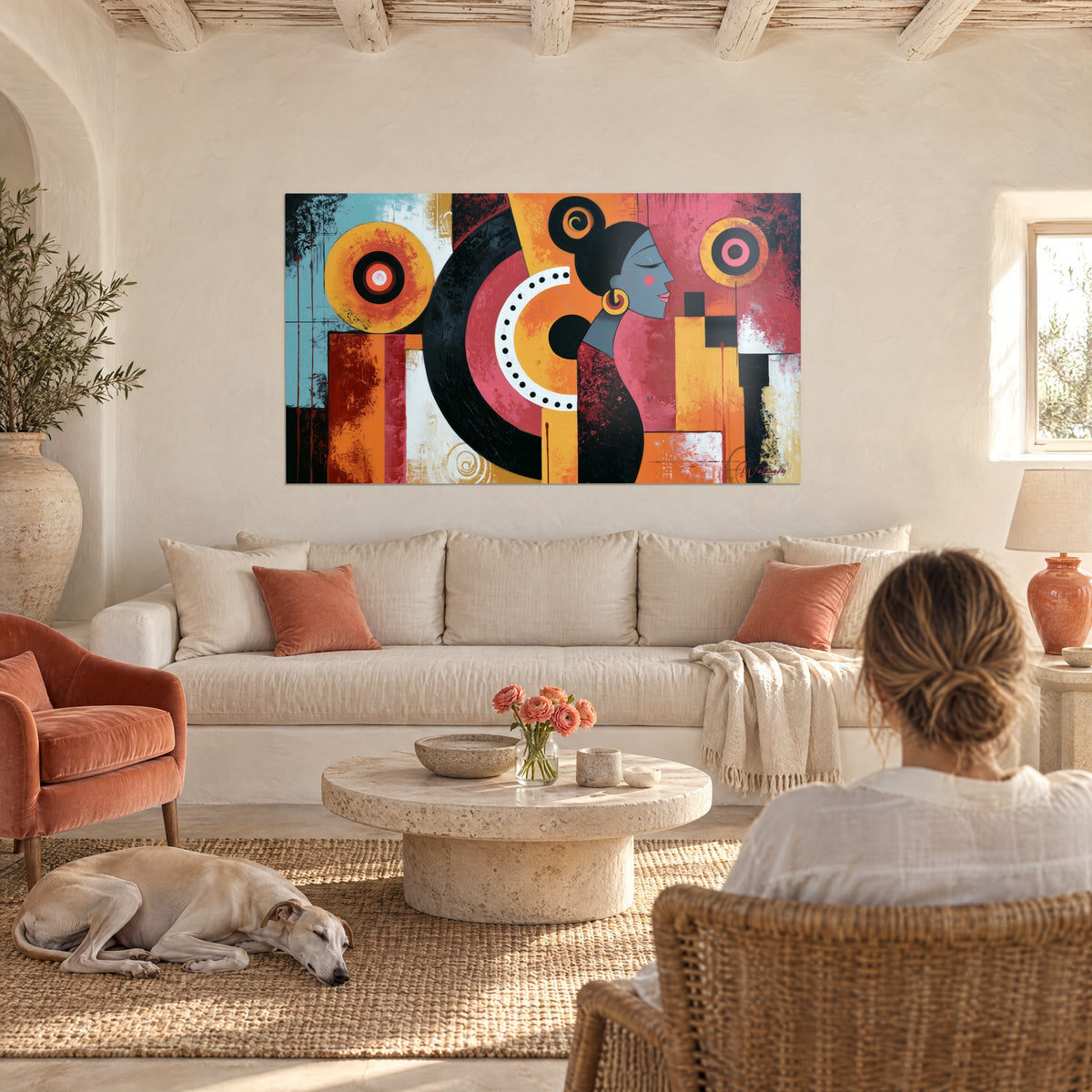 Quadro profilo femminile grigio con cerchi concentrici ocra e rosa, su parete bianca, donna di spalle, sopra un divano in un soggiorno luminoso