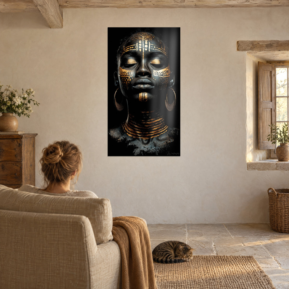 Cuadro figura femenina tatuada en dorado, tonos negro y cobre, pared beige de piedra de un salón, mujer de espaldas, gato atigrado