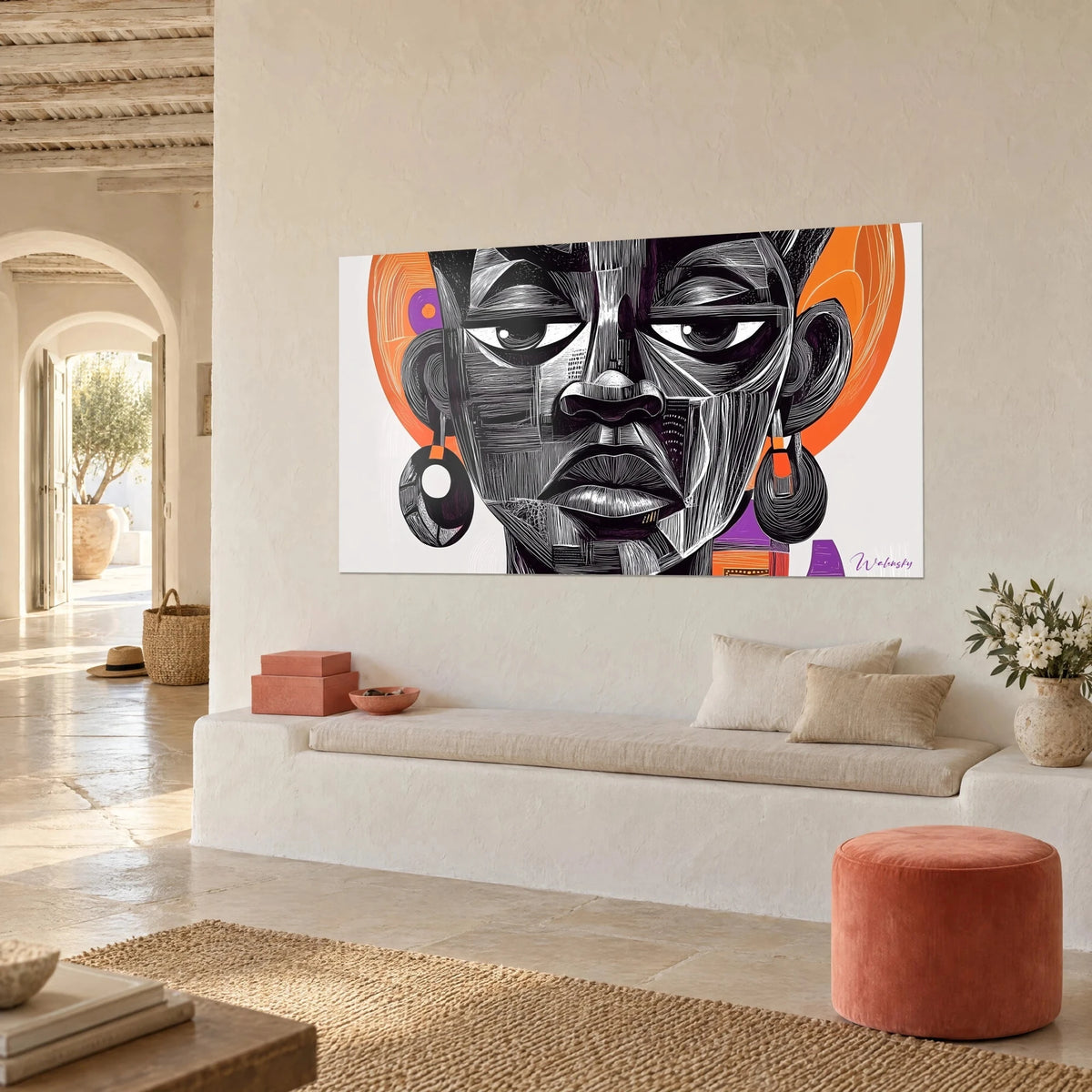 Tableau masque des ancêtres aux boucles d'oreilles rondes, orange et violet, sur mur blanc, banquette en alcôve