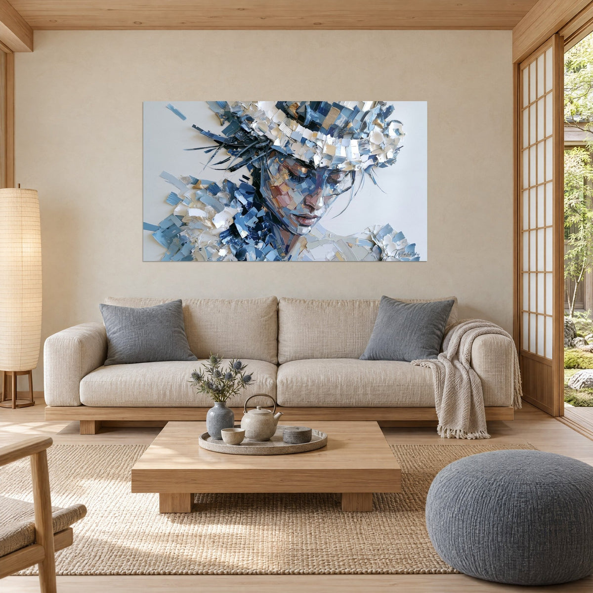 Tableau visage de femme aux paupières closes, coiffe de fragments bleu nuit et blanc, au-dessus d'un canapé dans un salon lumineux