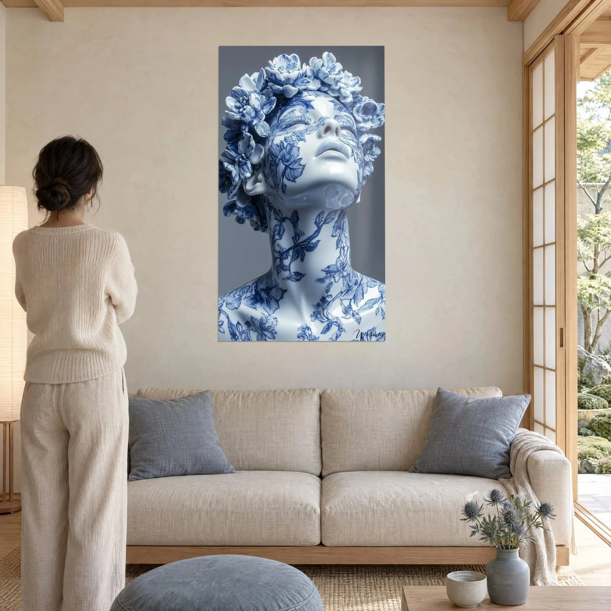 Wall art porcelain bust with cobalt blue flowers, face lifted, glossy glaze, above a sofa in a bright living room