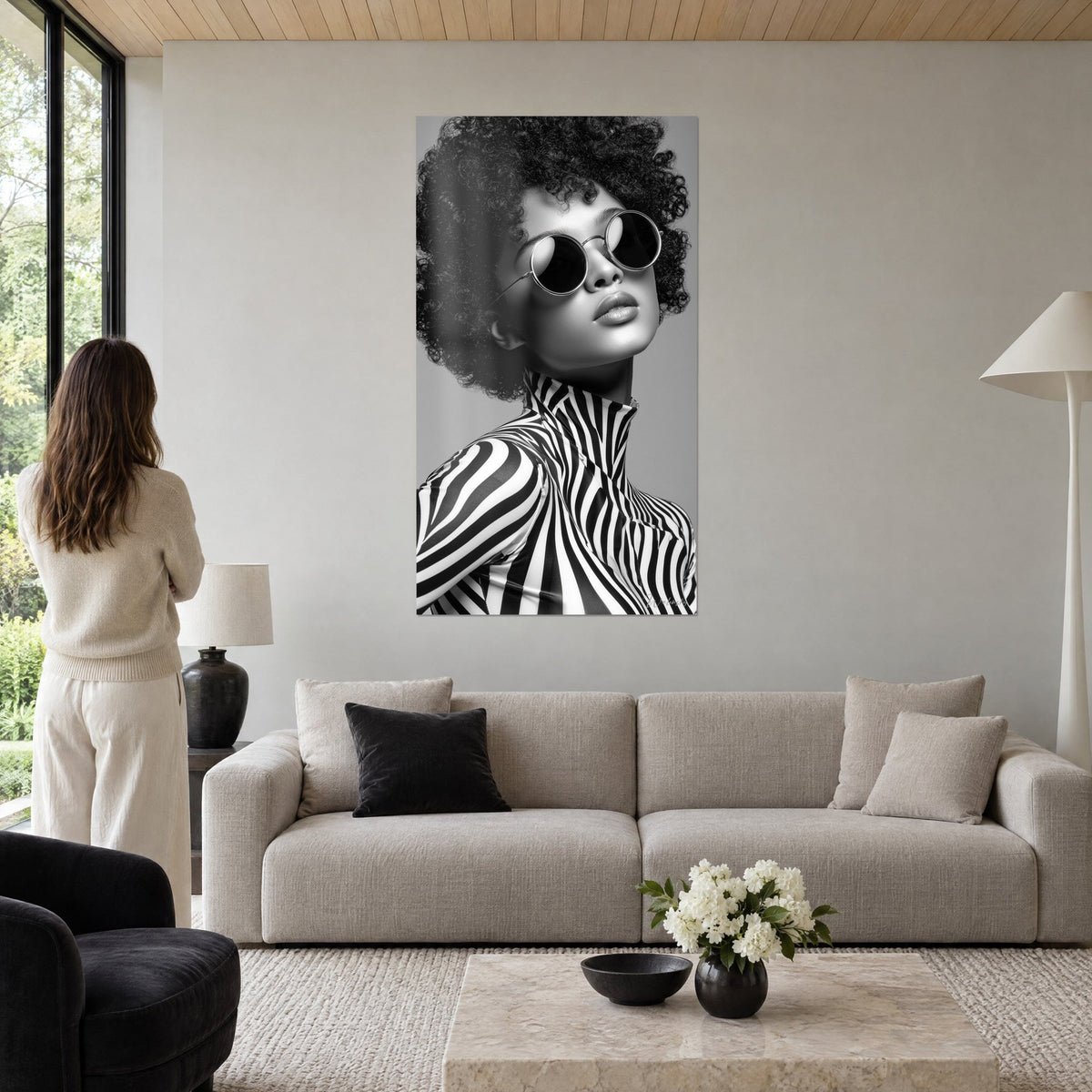 Tableau portrait afro en noir et blanc, lunettes rondes cerclées d'argent et col zébré, au-dessus d'un canapé dans un salon lumineux