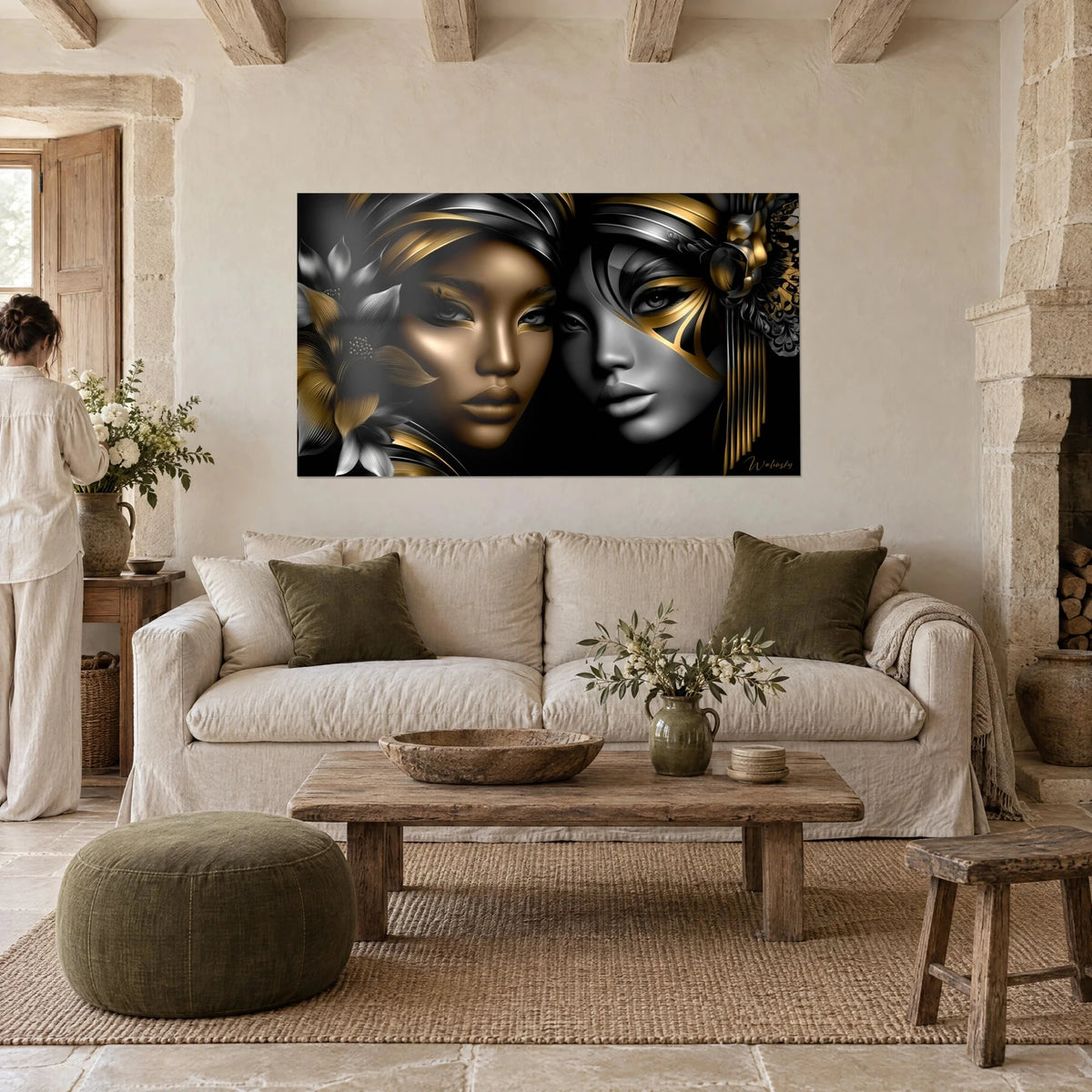 Wall art of two mirrored female faces, golden bronze skin and silvery grey cheek on a black background, hung above a sofa in a bright living room