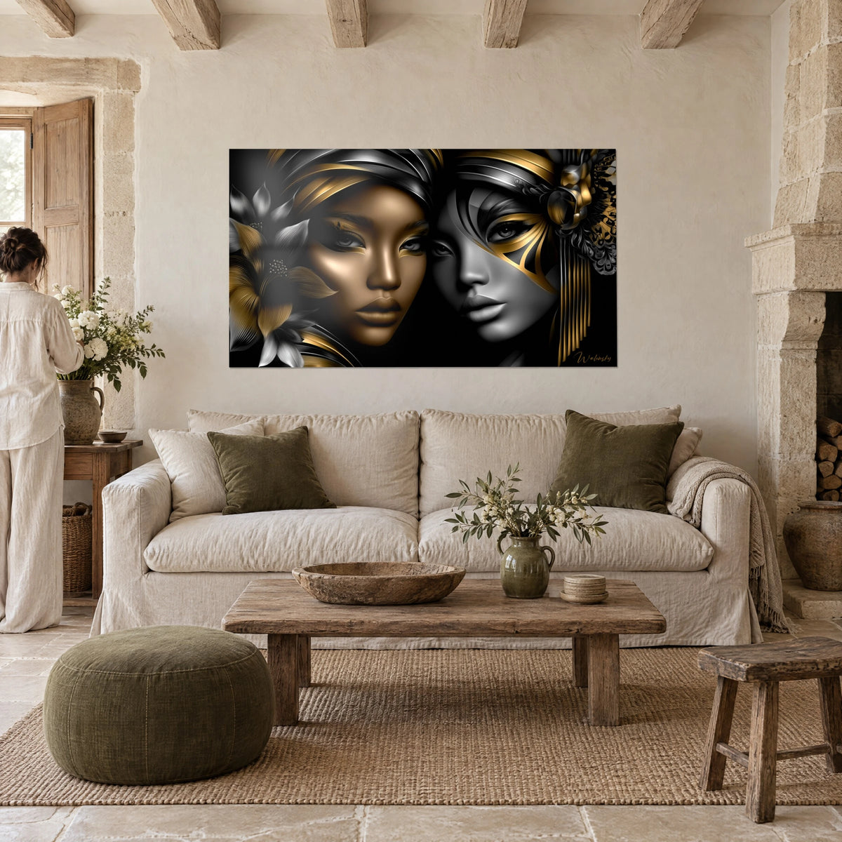 Cuadro de dos rostros femeninos reflejados, piel bronceada dorada y mejilla gris plateada sobre fondo negro, colgado encima de un sofá en un salón luminoso