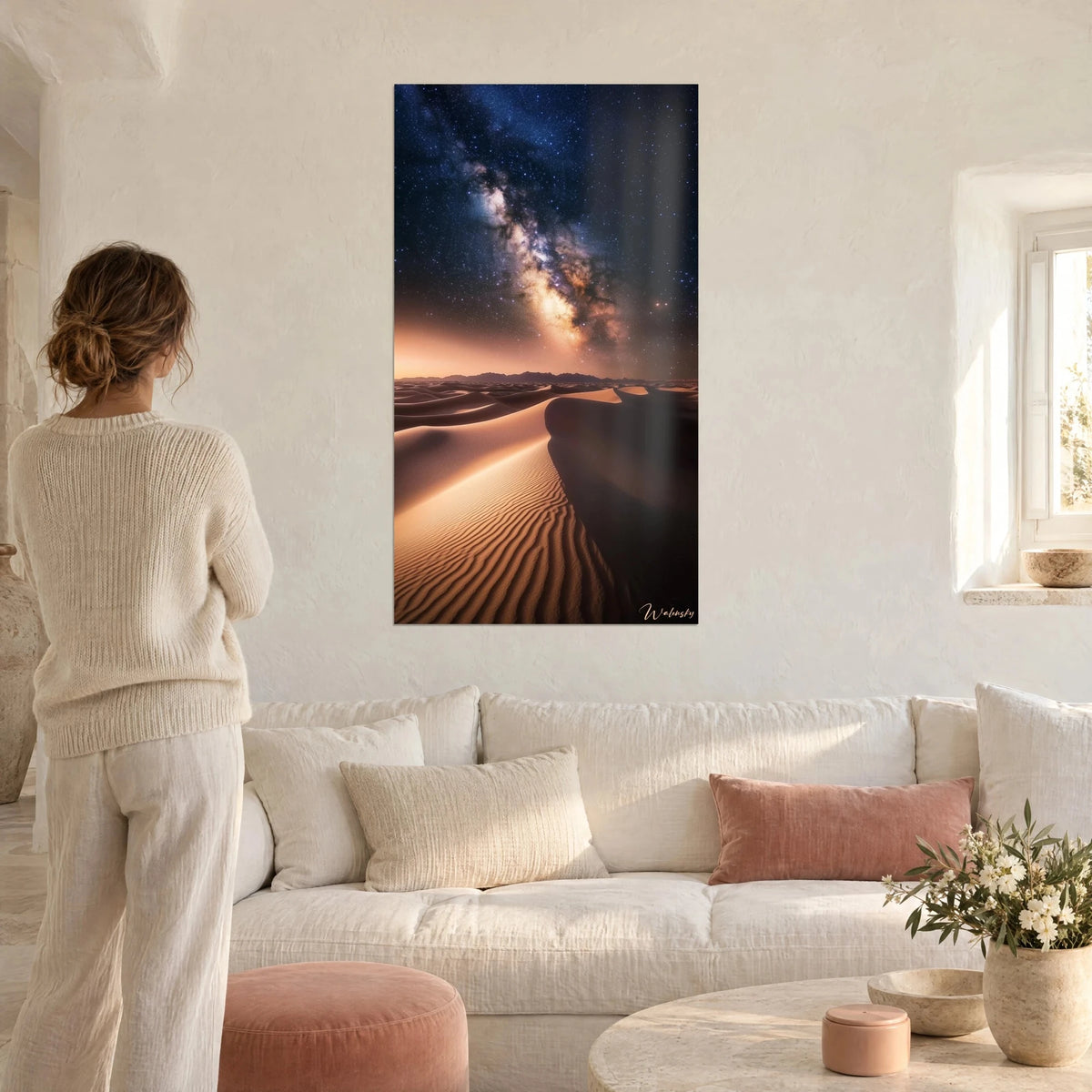 Tableau voie lactée flamboyante, dunes de sable cuivré et ciel bleu nuit, femme de dos au-dessus d'un canapé dans un salon lumineux