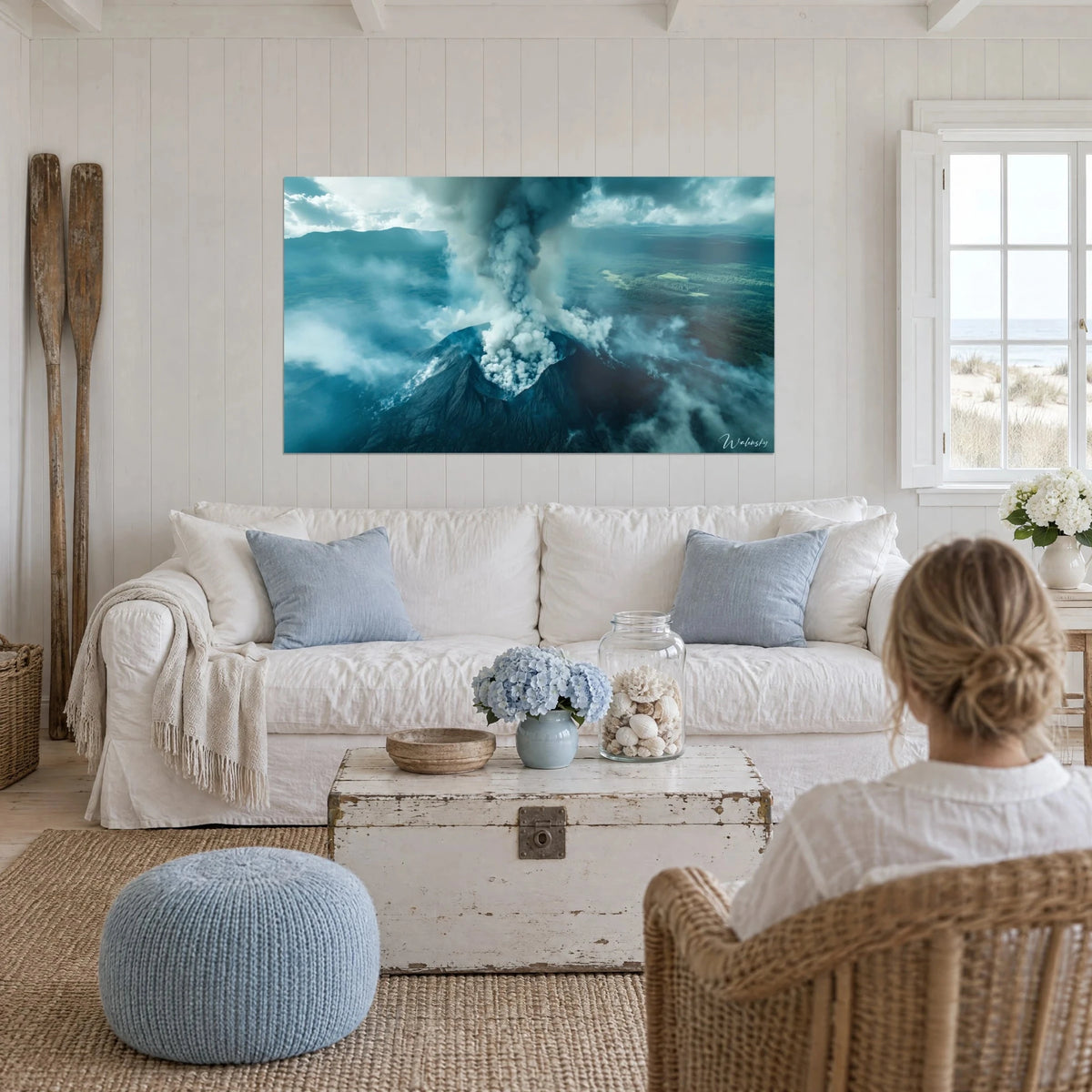 Wall art erupting volcano, grey plume of smoke over black slopes and petrol blue mist, above a sofa in a bright living room