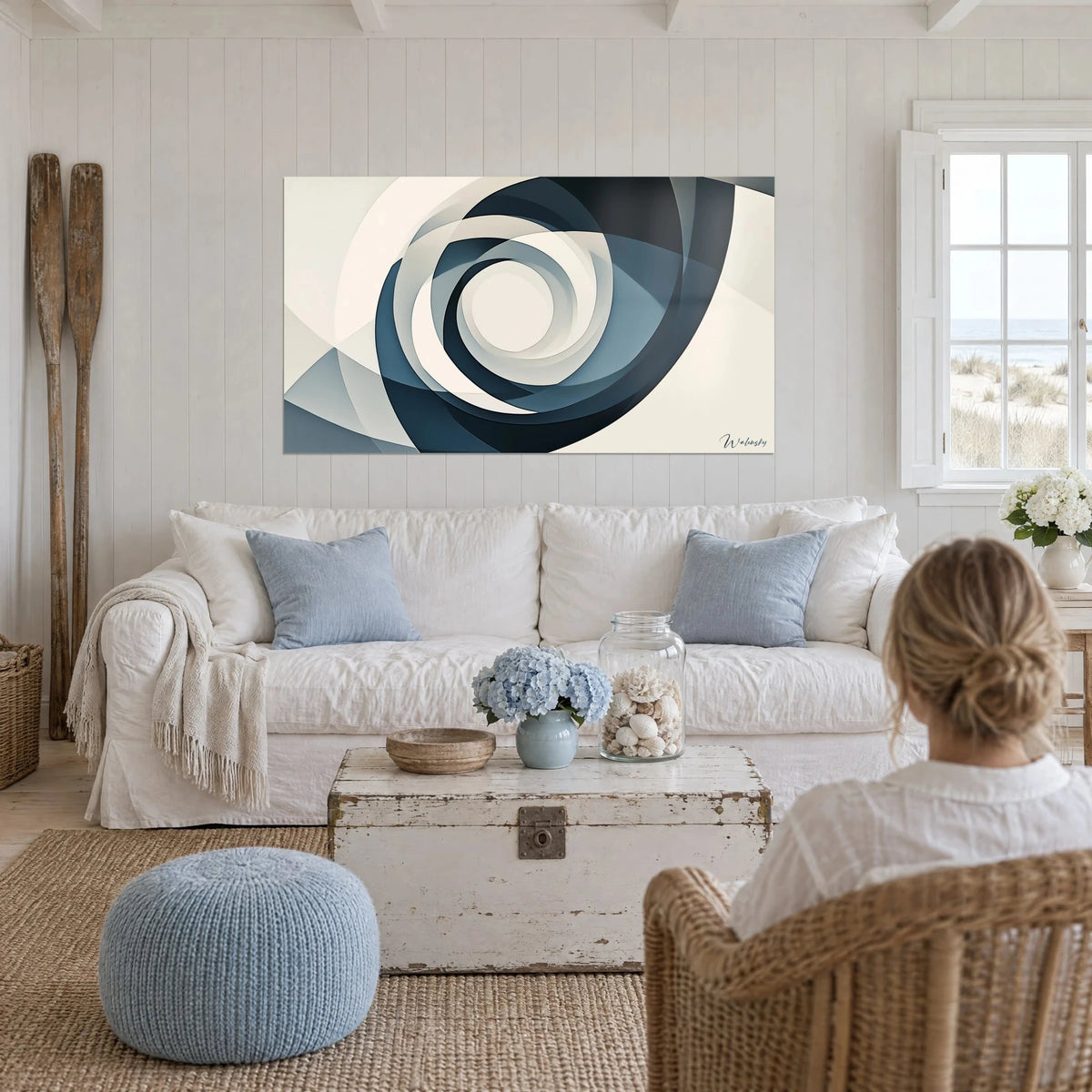 Quadro a spirale concentrica in blu ardesia e bianco crema, persona di spalle, sopra un divano in un soggiorno luminoso