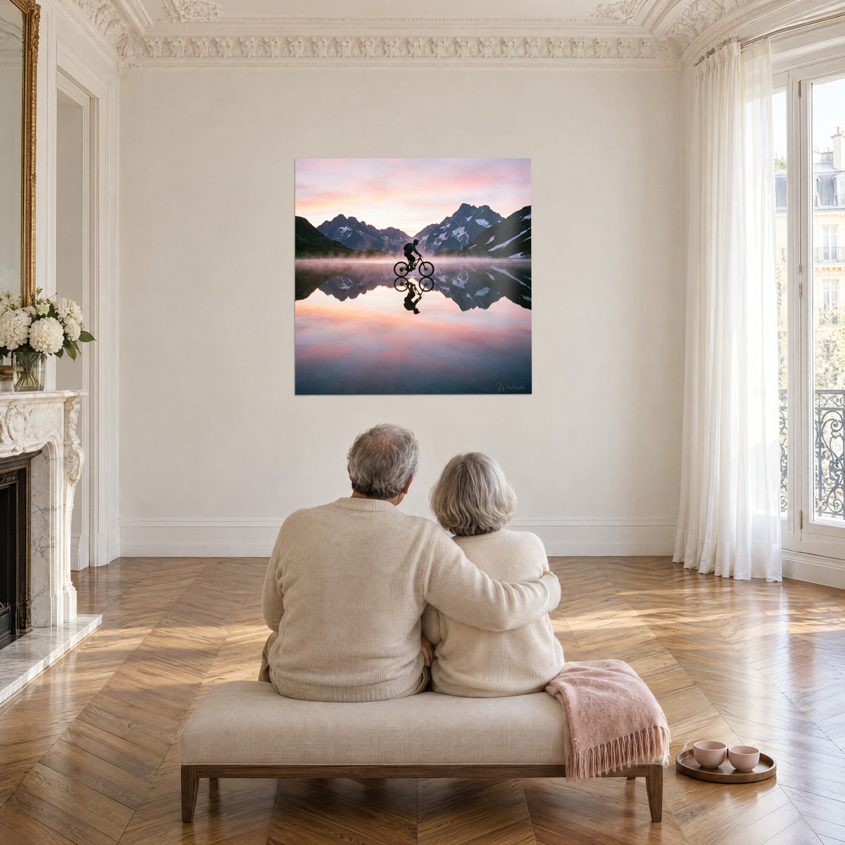 Schilderij alpine toppen weerspiegeld in een rustig meer, zwarte fietser, roze en blauwe verloop, tegenover een ouder echtpaar op een bank