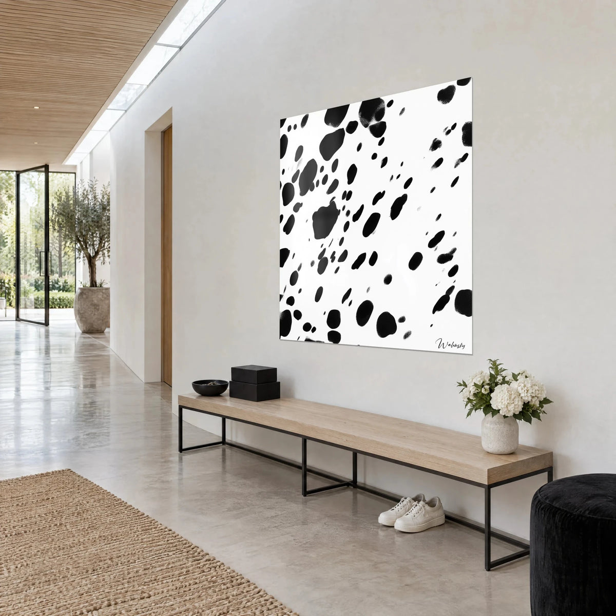 Wall art with a black and white dalmatian coat pattern, large splashes, seen three-quarter view on a light grey wall, glazed corridor