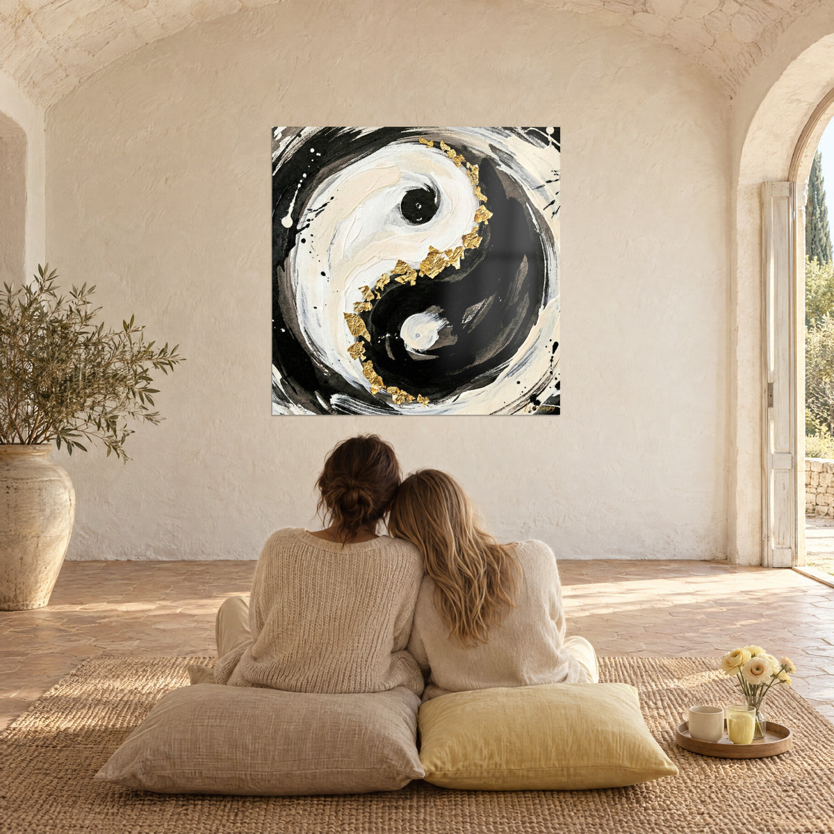 Πίνακας κύκλου yin yang με πιτσιλιές μαύρου μελανιού σε κρεμ φόντο, χρυσό περίγραμμα, δύο γυναίκες από πίσω καθισμένες σε μπεζ μαξιλάρια