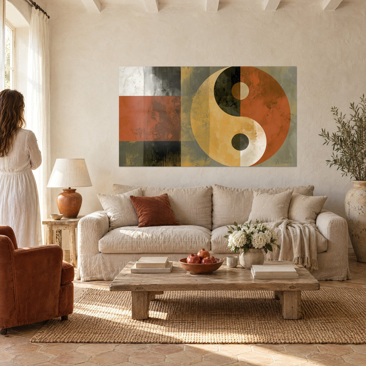 Πίνακας σύμβολο yin yang σε terracotta και ώχρα, γκρι και μαύρα πατινέ τεταρτημόρια, δύο άνθρωποι από πίσω πάνω από έναν καναπέ σε ένα φωτεινό σαλόνι