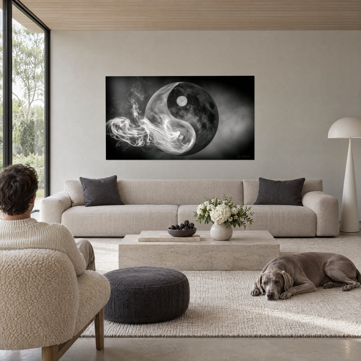 Wall art smoky yin yang, grey cratered moon and white wisps on black background, above a sofa in a bright living room