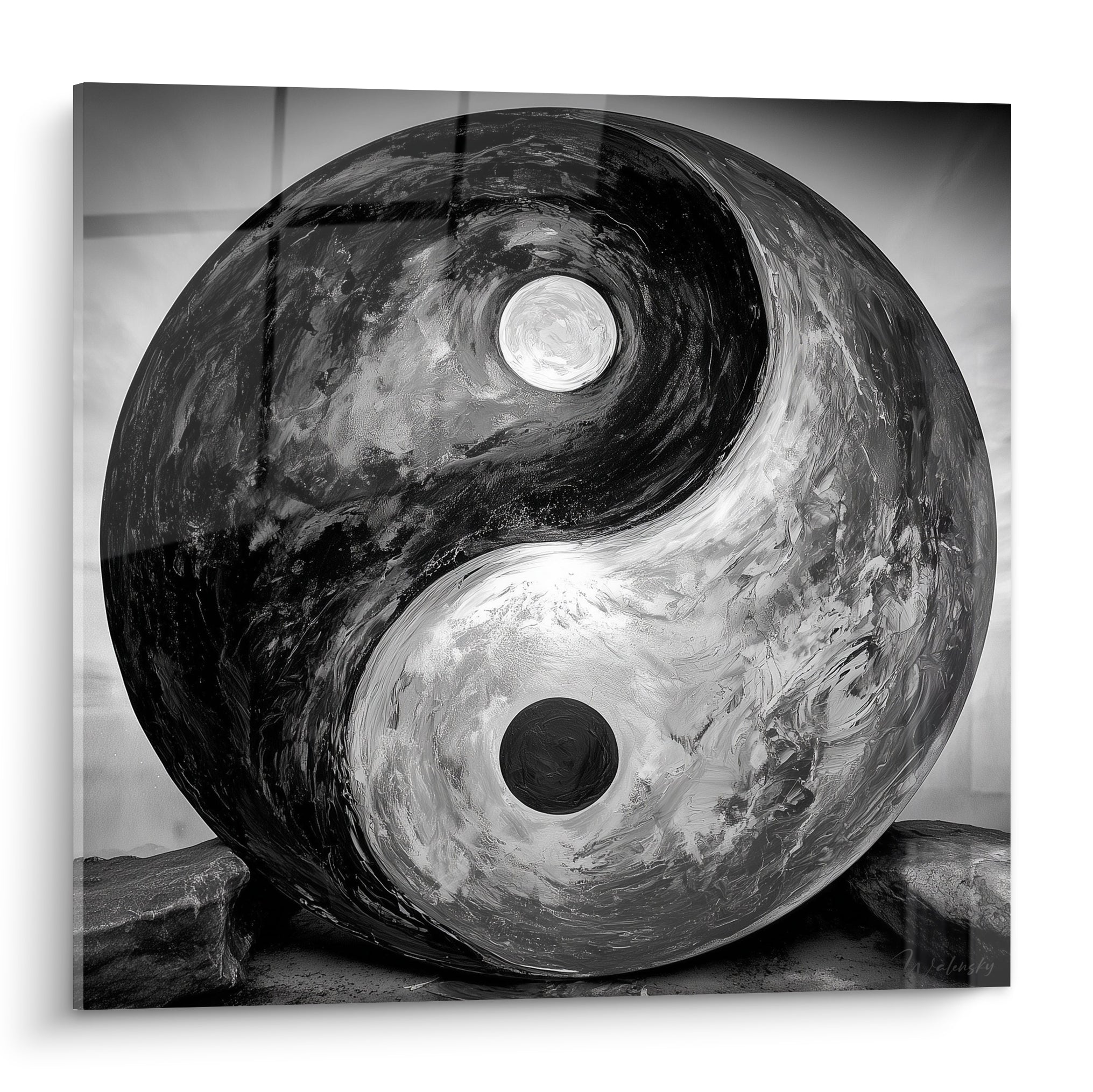Sphère Yin Yang noire et blanche texturée posée sur des rochers gris minéraux