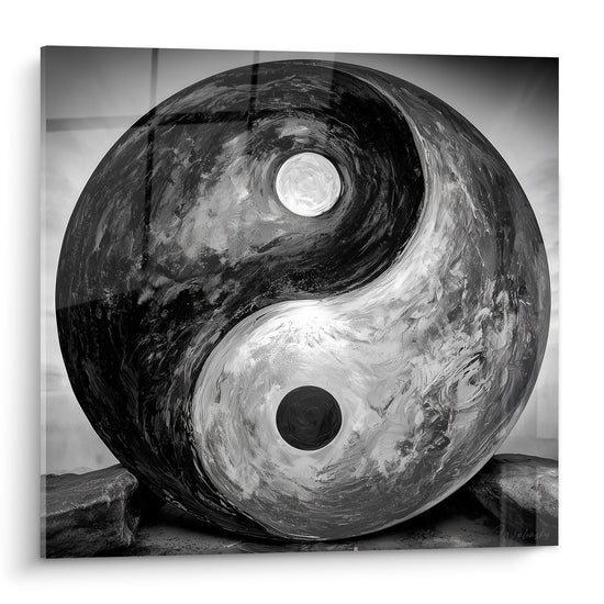 Sphère Yin Yang noire et blanche texturée posée sur des rochers gris minéraux