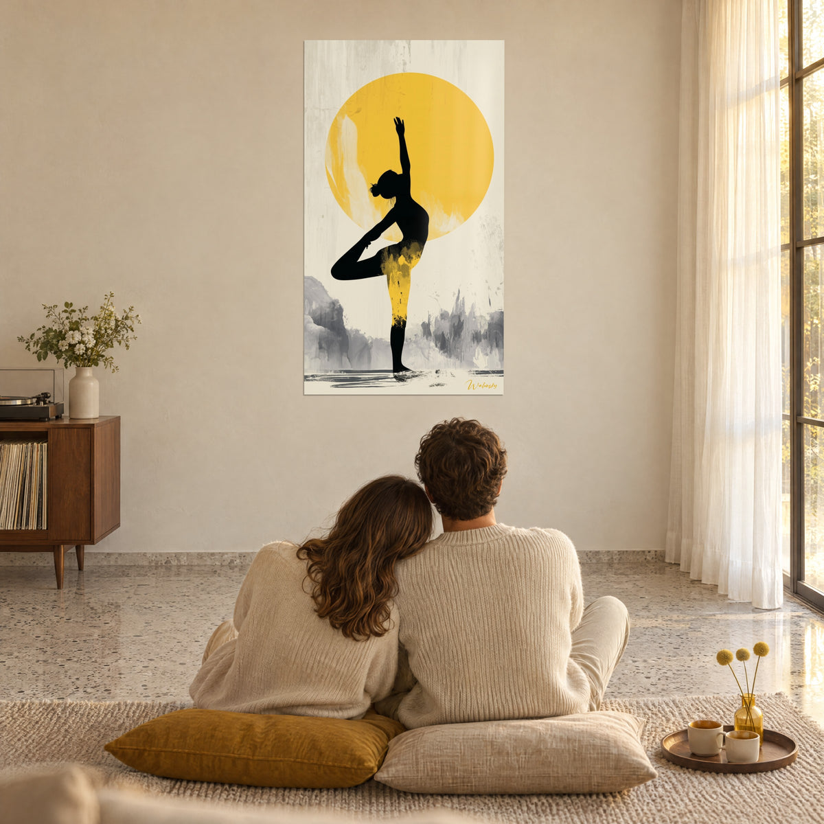 Quadro ombra nera di una yogini su un astro giallo vivo, sfondo beige, rocce grigie, coppia abbracciata di spalle su cuscini color senape