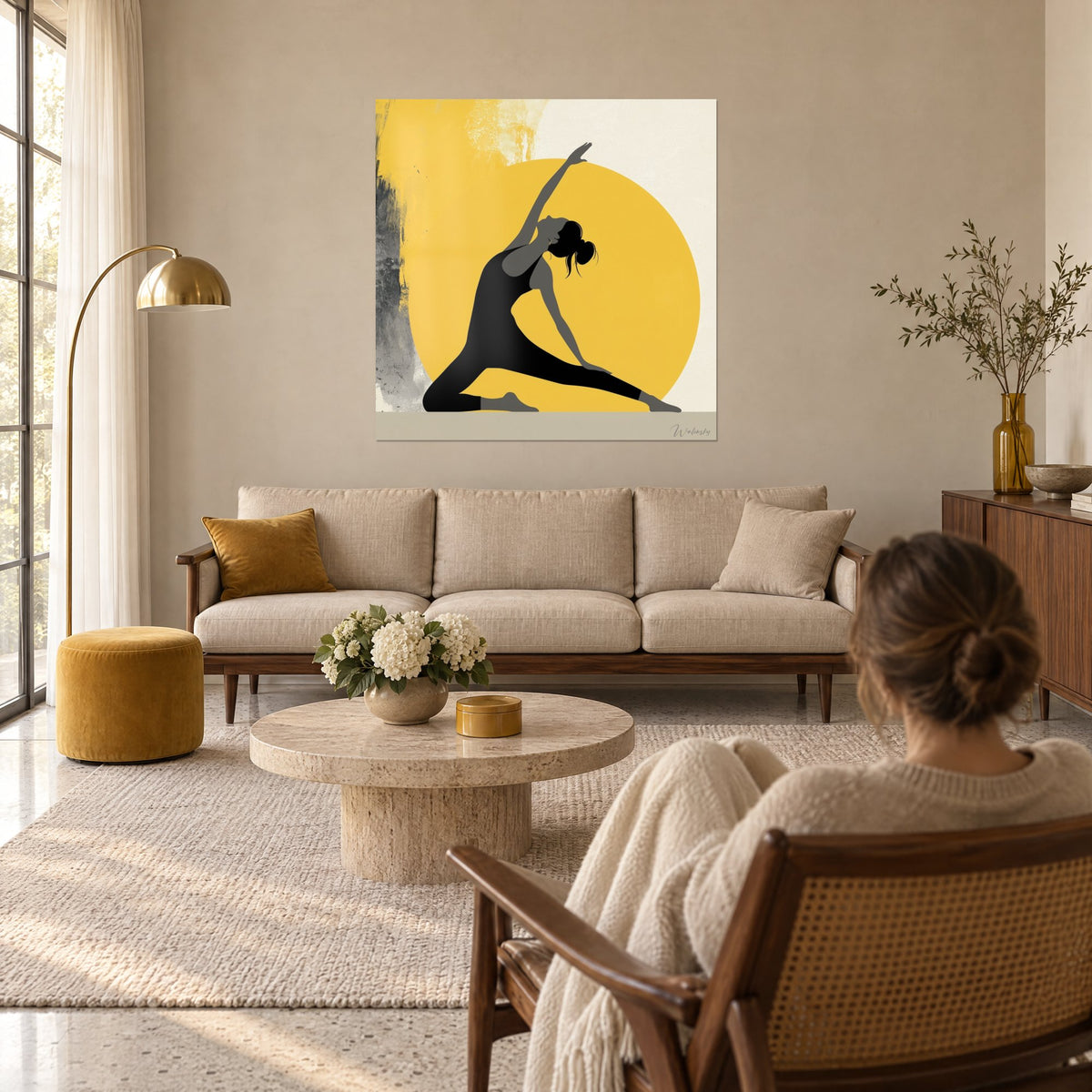 Wall art black silhouette in yoga pose on a mustard yellow disc and ivory background, above a sofa in a bright living room