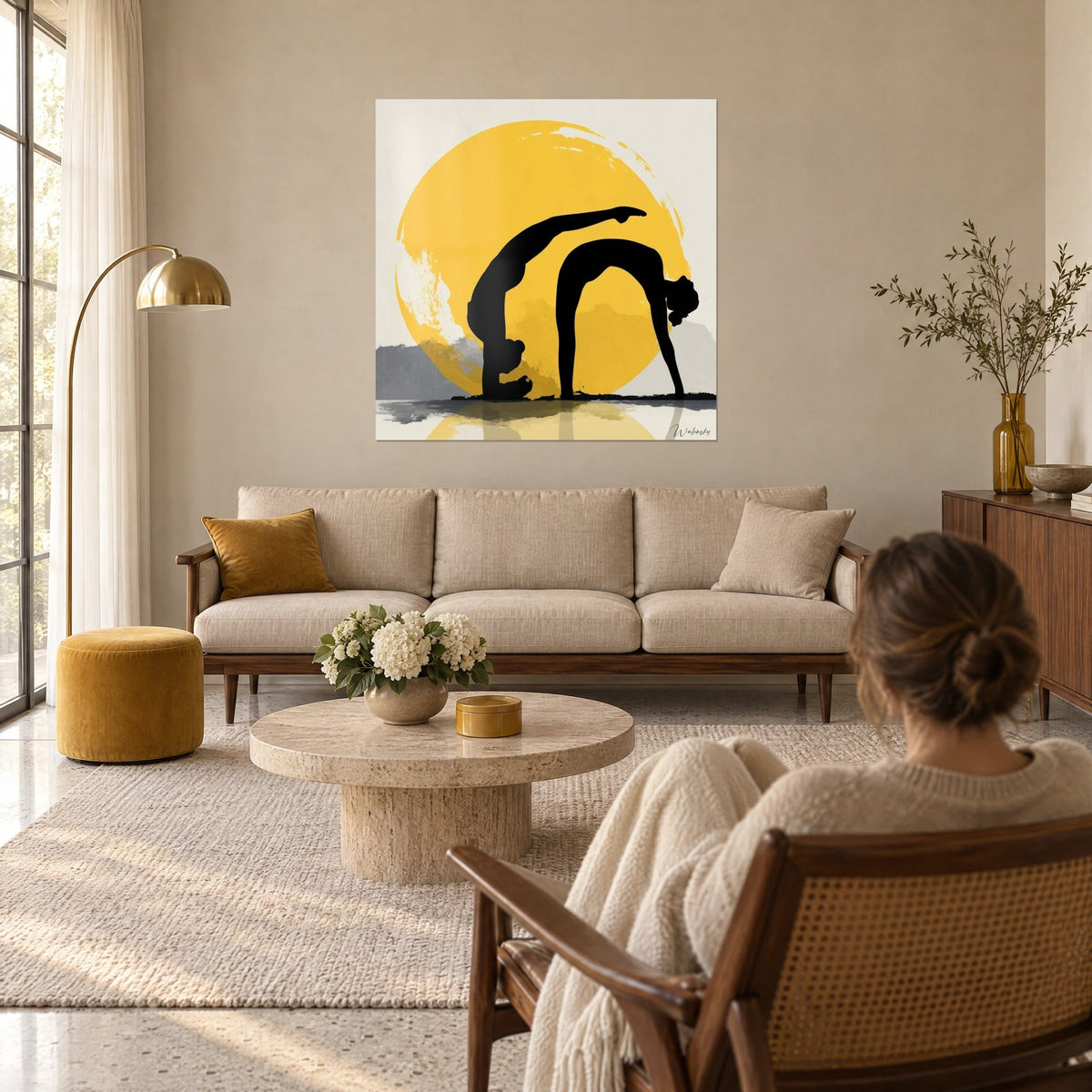 Schilderij zwarte silhouetten in brugpositie voor een saffraangele zon, crème en grijze achtergrond, vrouw met de rug naar de kijker op een bank in een lichte woonkamer