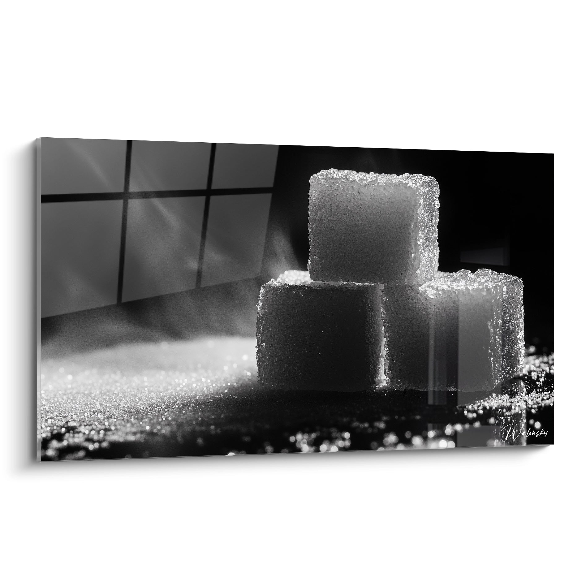 Un tableau sucre en noir et blanc mettant en scène trois cubes de sucre empilés, illuminés par une lumière rasante. Les textures granuleuses et les ombres profondes renforcent le contraste visuel.

