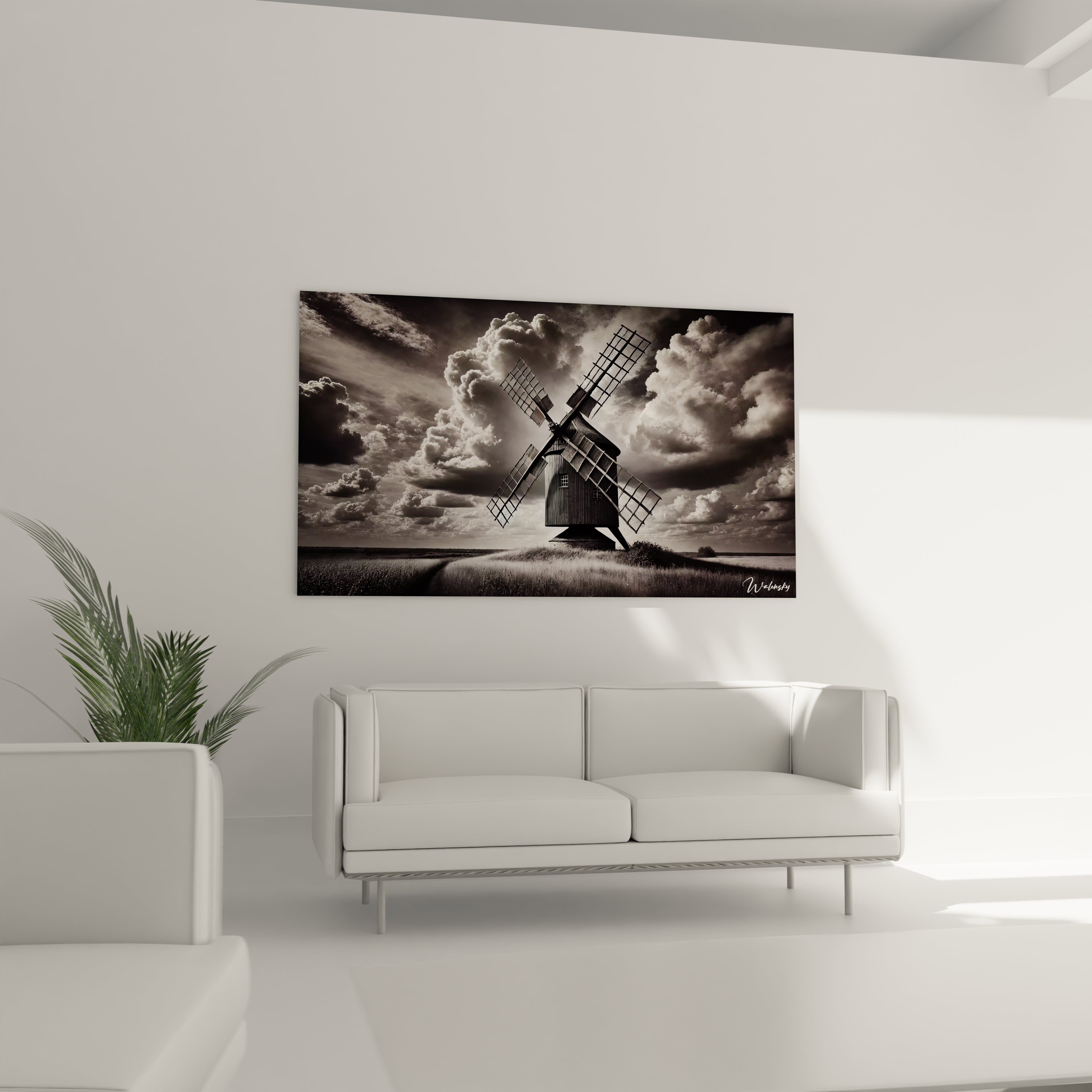 Tableau noir et blanc place au-dessus d’un canape dans un salon moderne montrant un moulin rural sous un ciel dramatique, parfait pour un decor raffine.
