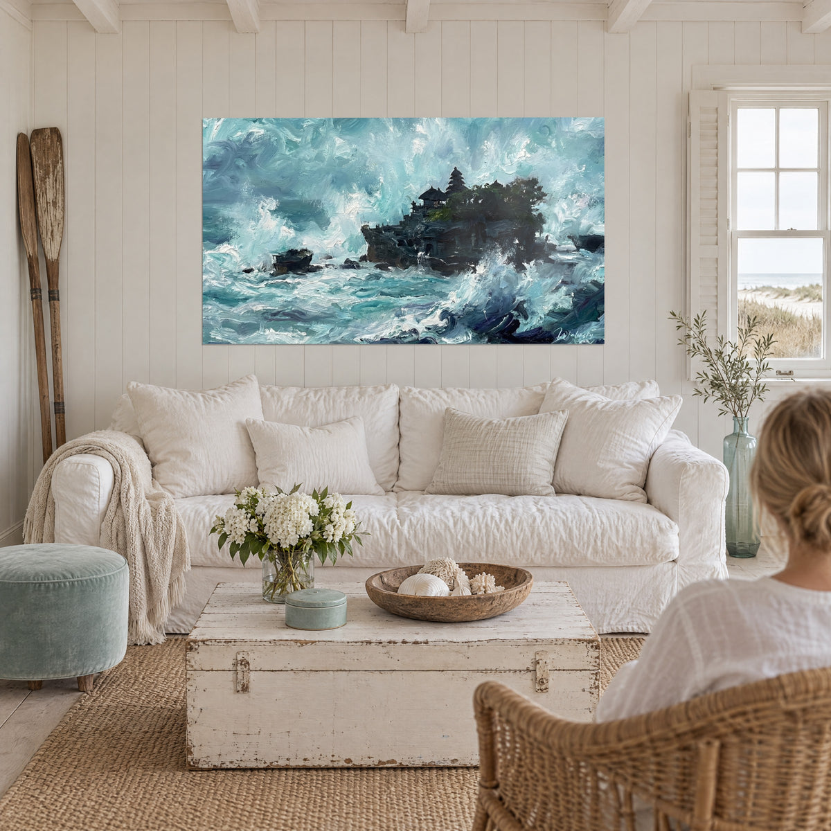 Wall art black Balinese temple on its rock, turquoise waves and white foam, above a sofa in a bright living room