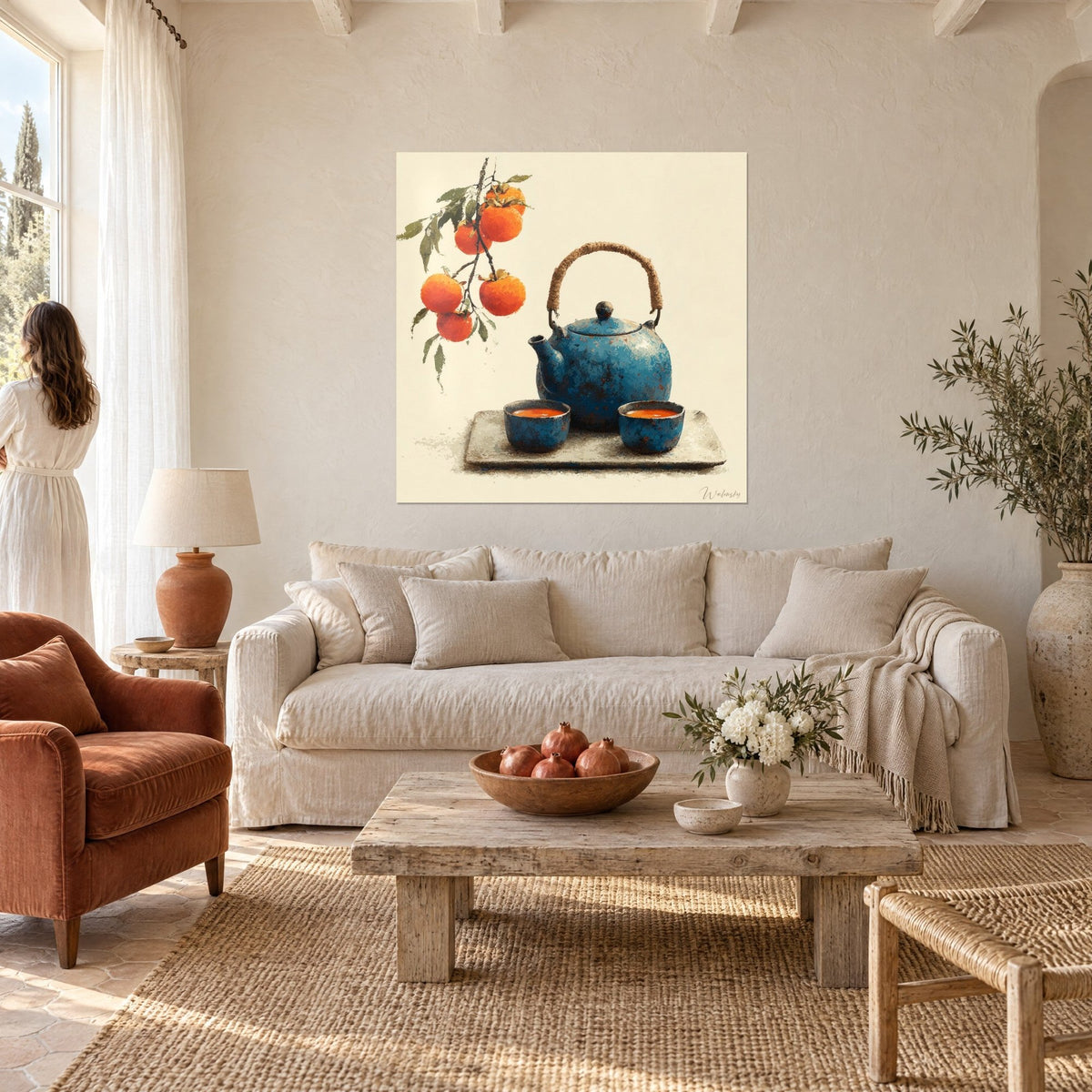 Wall art cobalt blue enamelled cast iron teapot, orange persimmons on their branch, cream background, above a sofa in a bright living room