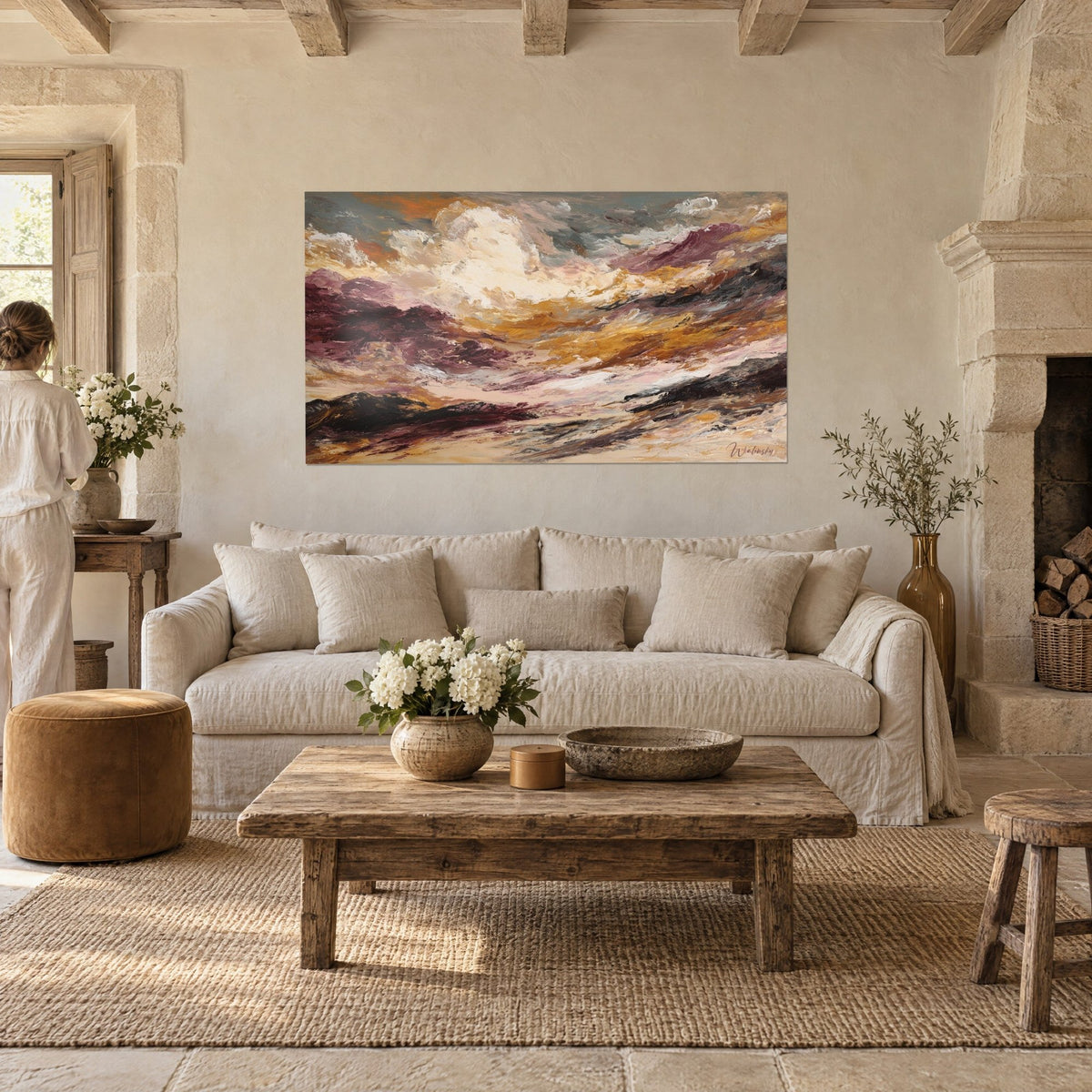 Wall art of a stormy landscape in ochre and burgundy, turbulent cream sky, above a sofa in a bright living room