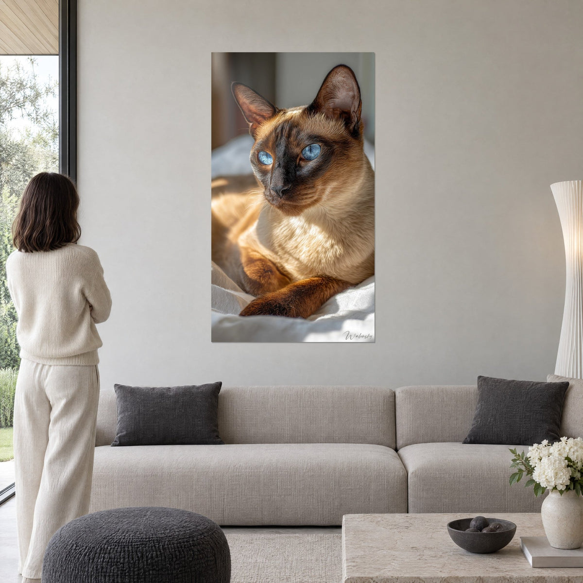 Tableau chat tonkinois aux yeux bleus, pelage miel et masque brun, femme de dos, au-dessus d'un canapé dans un salon lumineux