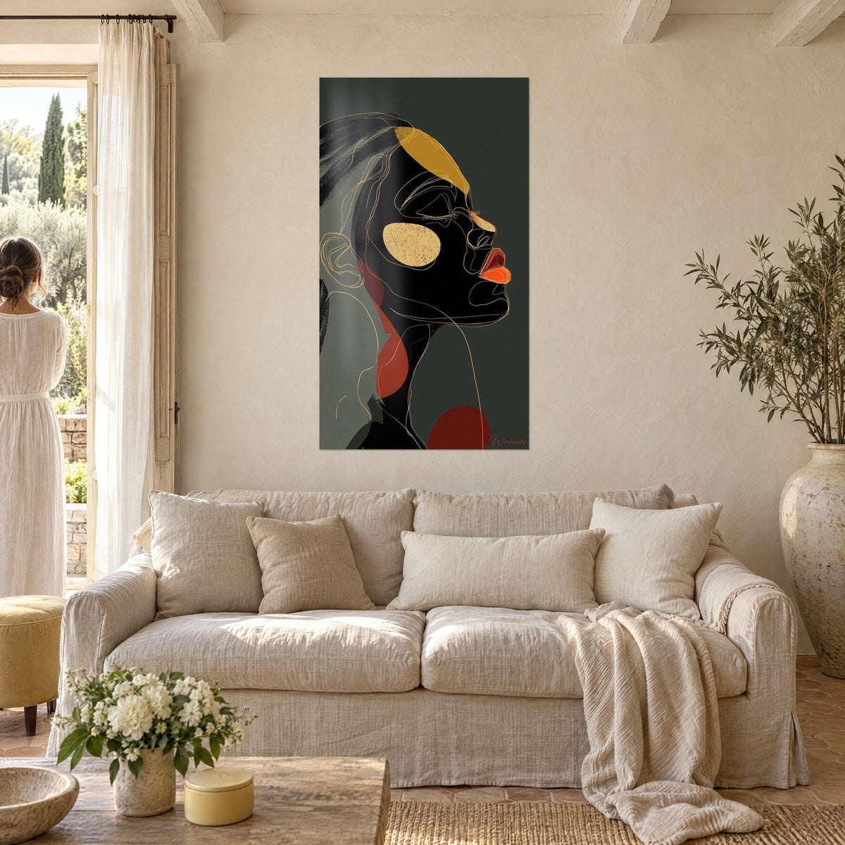 Wall art portrait of a Black woman in profile, golden cheeks and orange lips on grey background, above a sofa in a bright living room