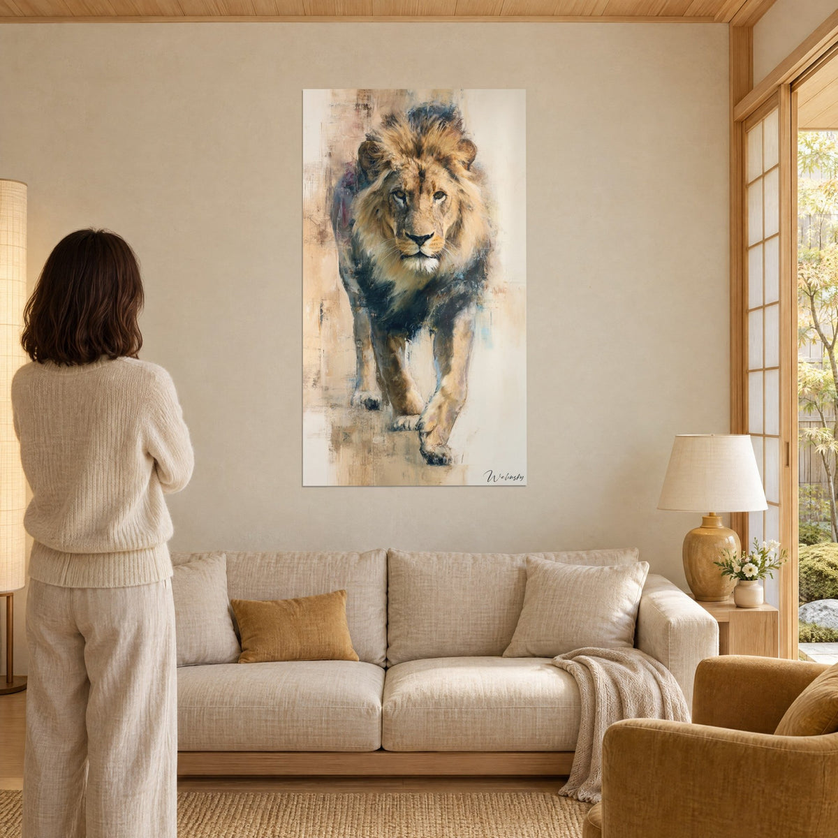 Gemälde Löwe mit goldgelber Mähne, der auf uns zukommt, in Beige- und Nachtblau-Tönen, Frau von hinten, über einem Sofa in einem hellen Wohnzimmer
