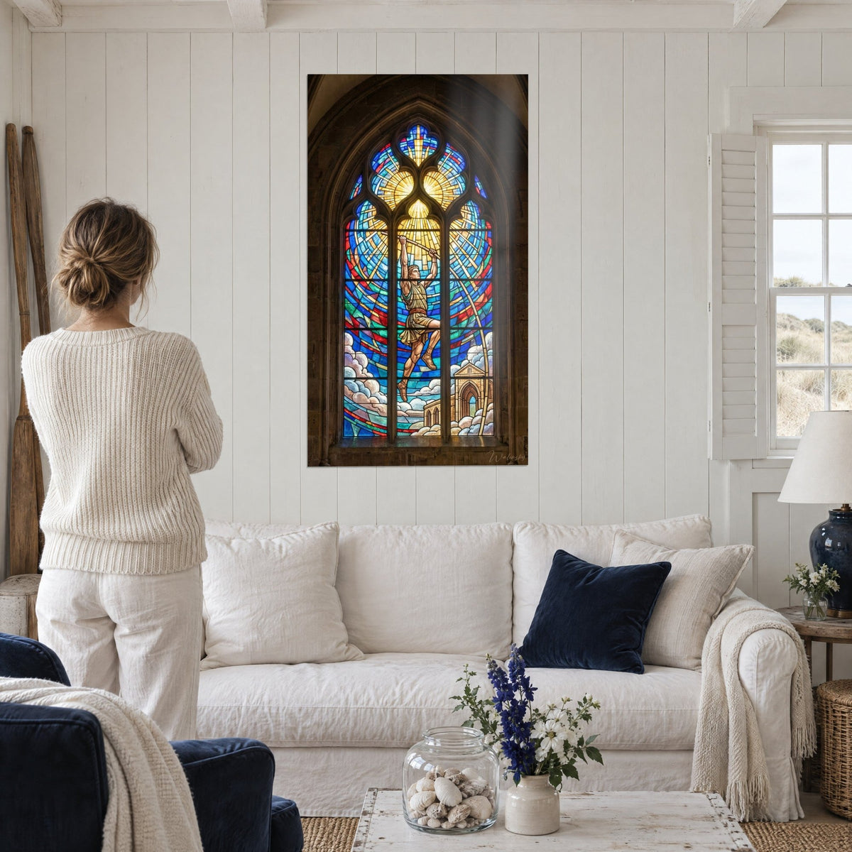 Tableau vitrail d'un athlète bondissant, perche levée, bleu cobalt et or, une femme de dos au-dessus d'un canapé dans un salon lumineux