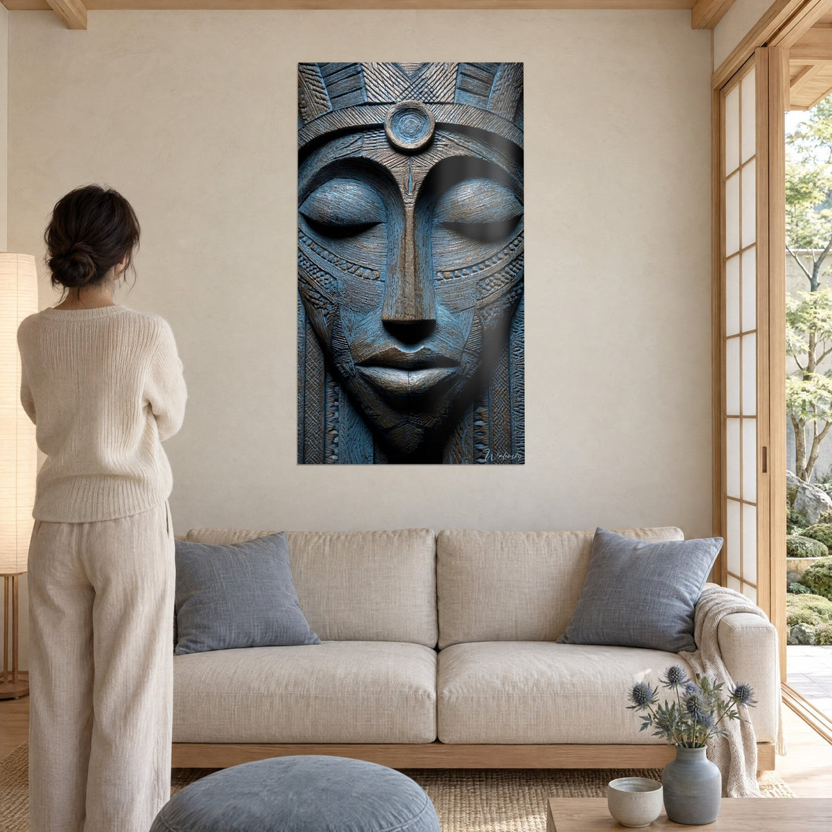 Quadro maschera africana scolpita con palpebre chiuse, blu ardesia e bronzo, diadema a disco, appeso sopra un divano in un soggiorno luminoso