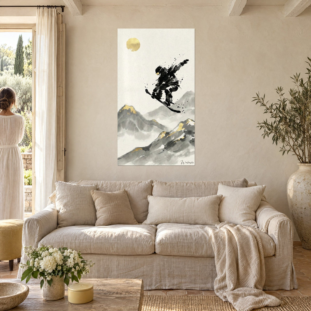 Wall art of a black snowboarder mid-jump before a golden sun, grey peaks, above a sofa in a bright living room