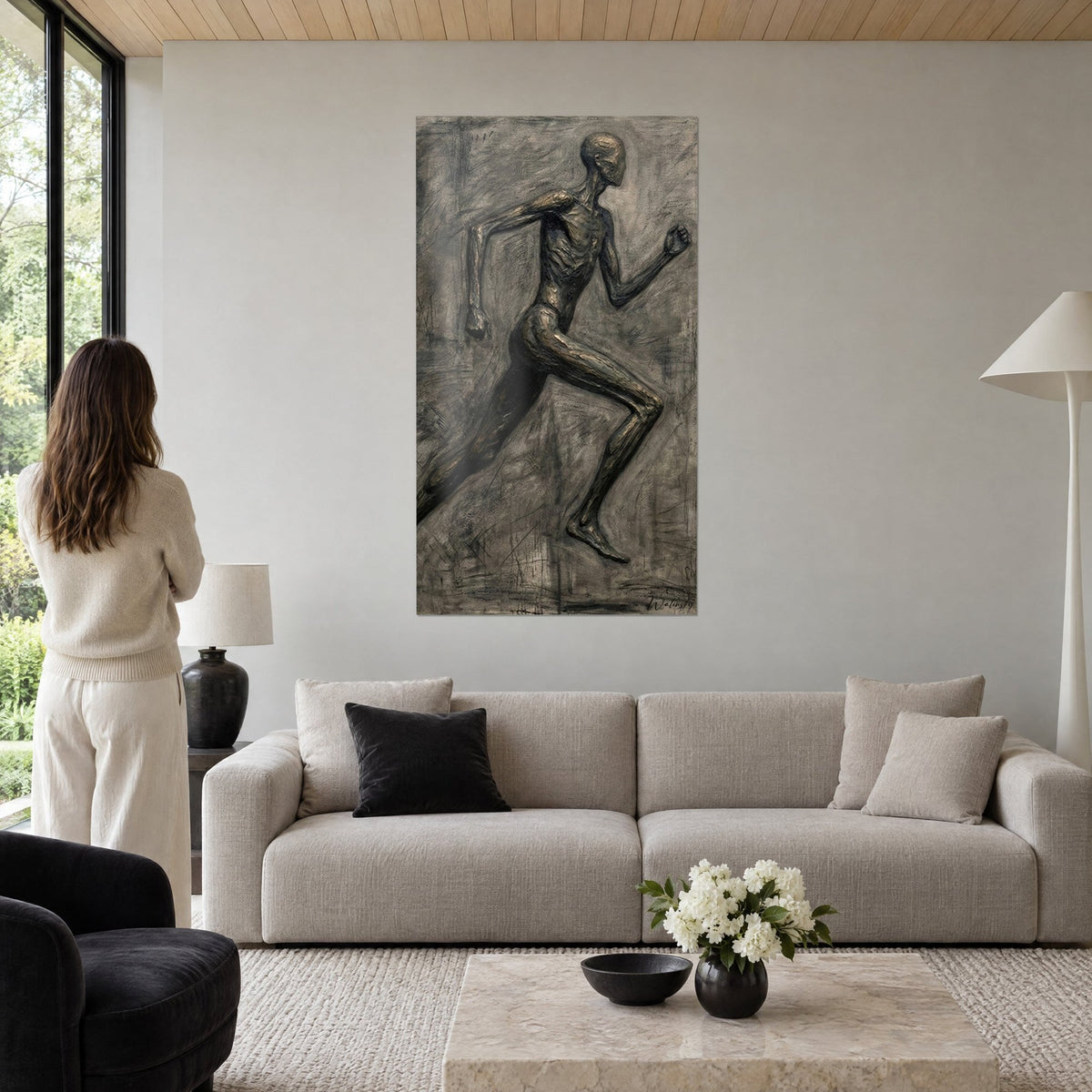 Wall art slender runner in bronze relief, anthracite grey and coppery brown, stretched stride, above a sofa in a bright living room