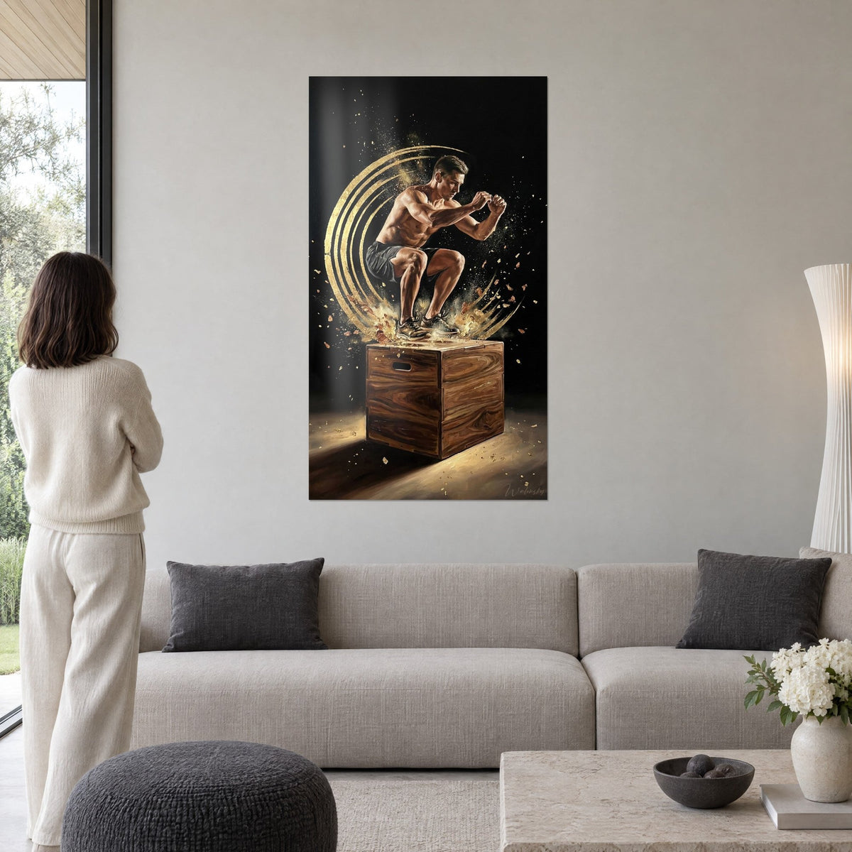 Wall art of a bare-chested athlete leaping over a box, golden rings and black background, above a sofa in a bright living room