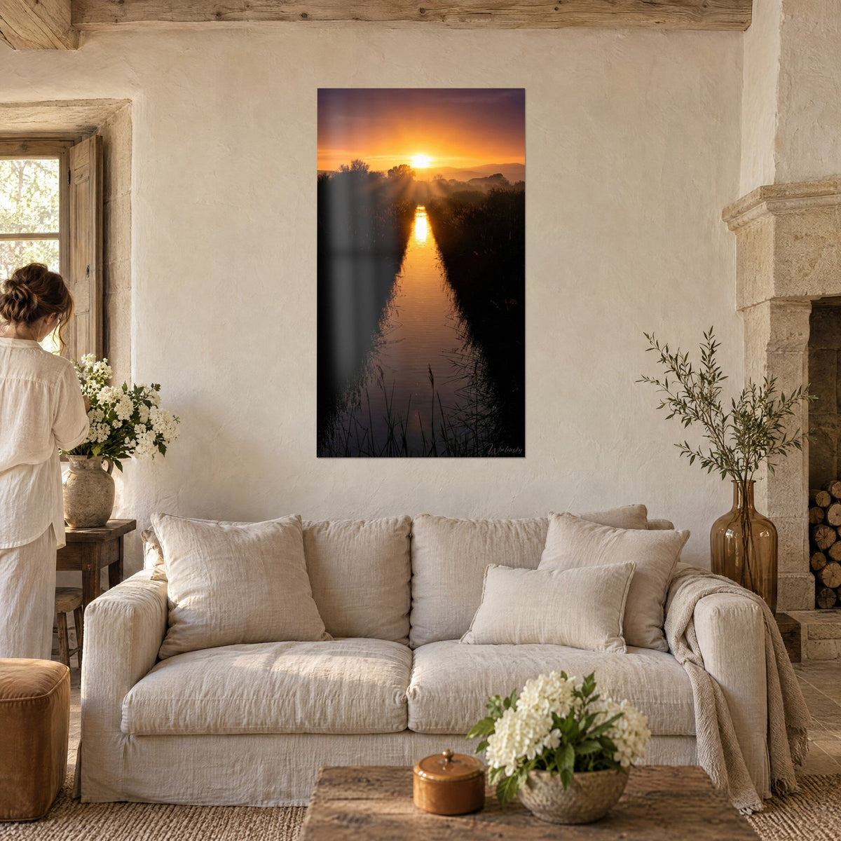 Gemälde eines schmalen Kanals, der eine orangefarbene Sonne zwischen dunklen Schilfrohren spiegelt, purpurner Himmel, über einem Sofa in einem hellen Wohnzimmer