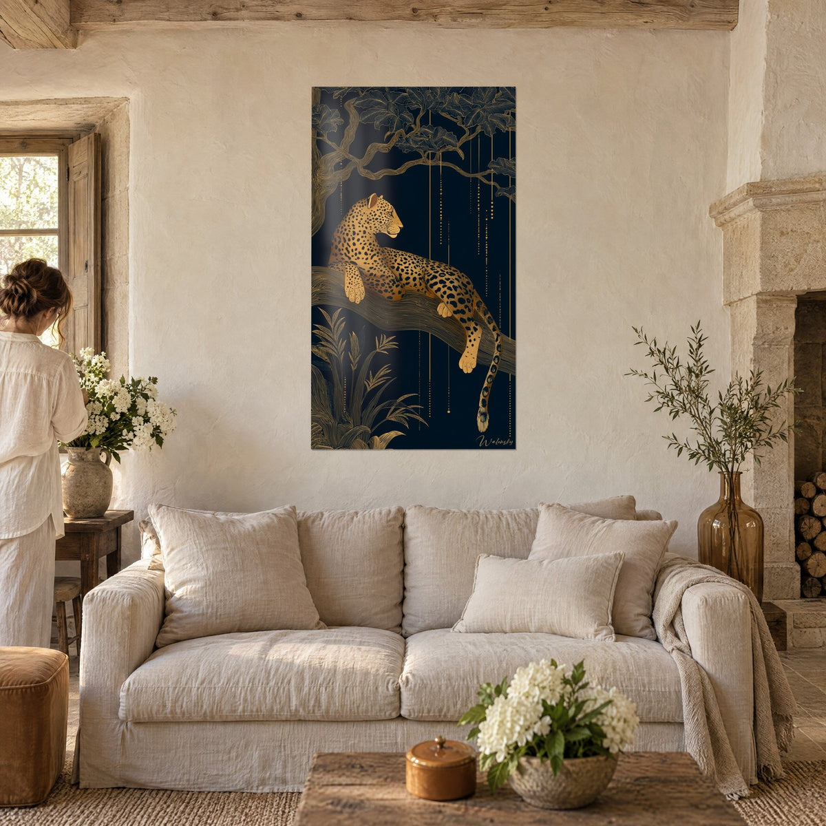 Schilderij van een gouden luipaard die op zijn tak ligt, nachtblauwe achtergrond en koperkleurig loof, boven een bank in een lichte woonkamer