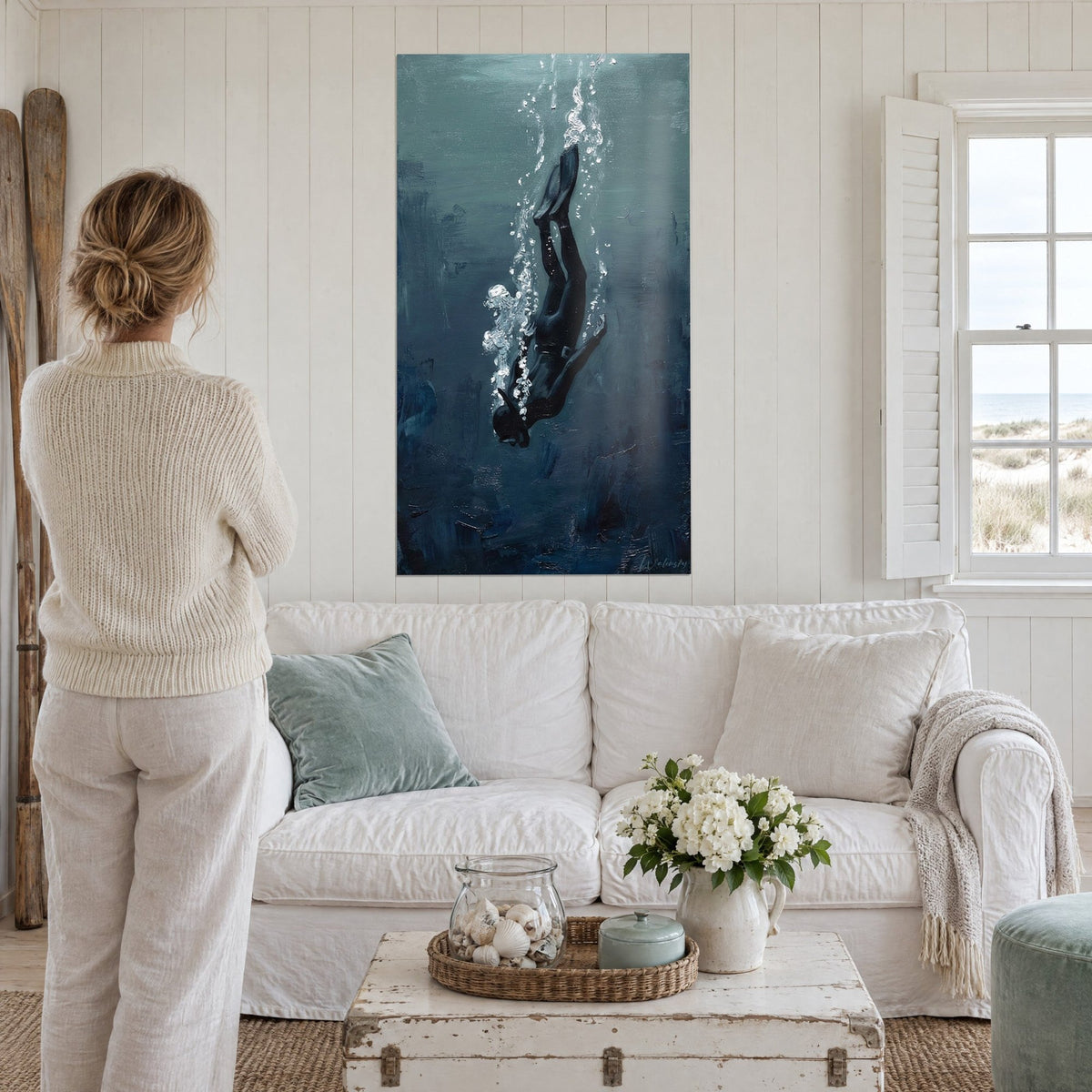 Wall art freediver in black wetsuit, fins pointing up, white bubbles on blue-grey background, above a sofa in a bright living room