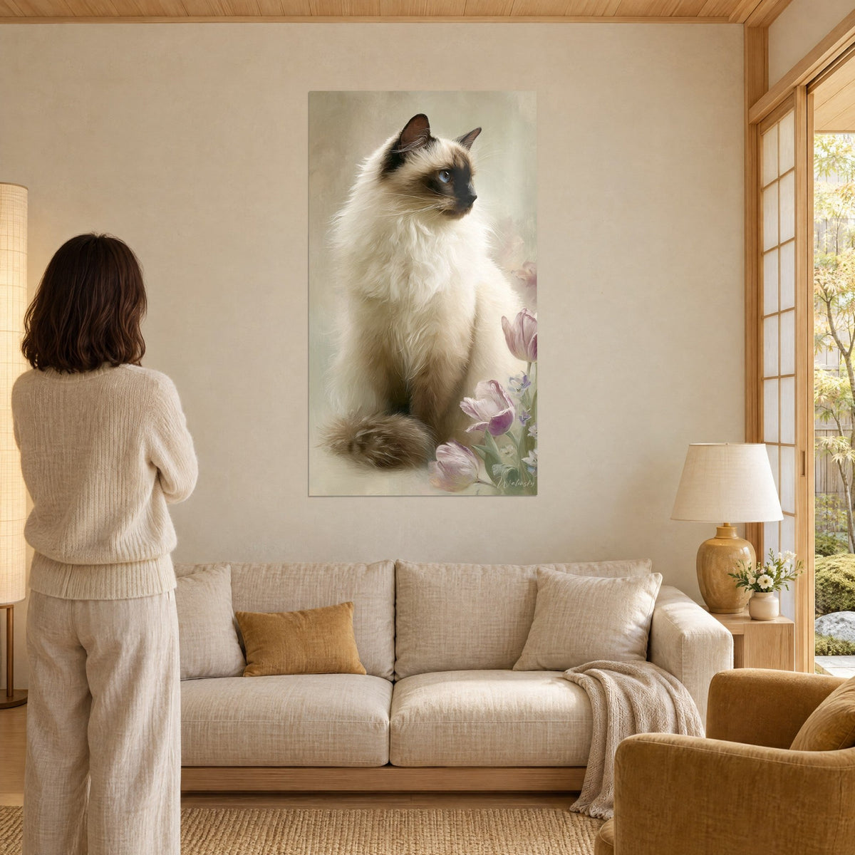 Πίνακας γάτα Birman με μπλε μάτια, κρεμ τρίχωμα και καφέ μάσκα, ροζ τουλίπες, πάνω από καναπέ σε φωτεινό σαλόνι