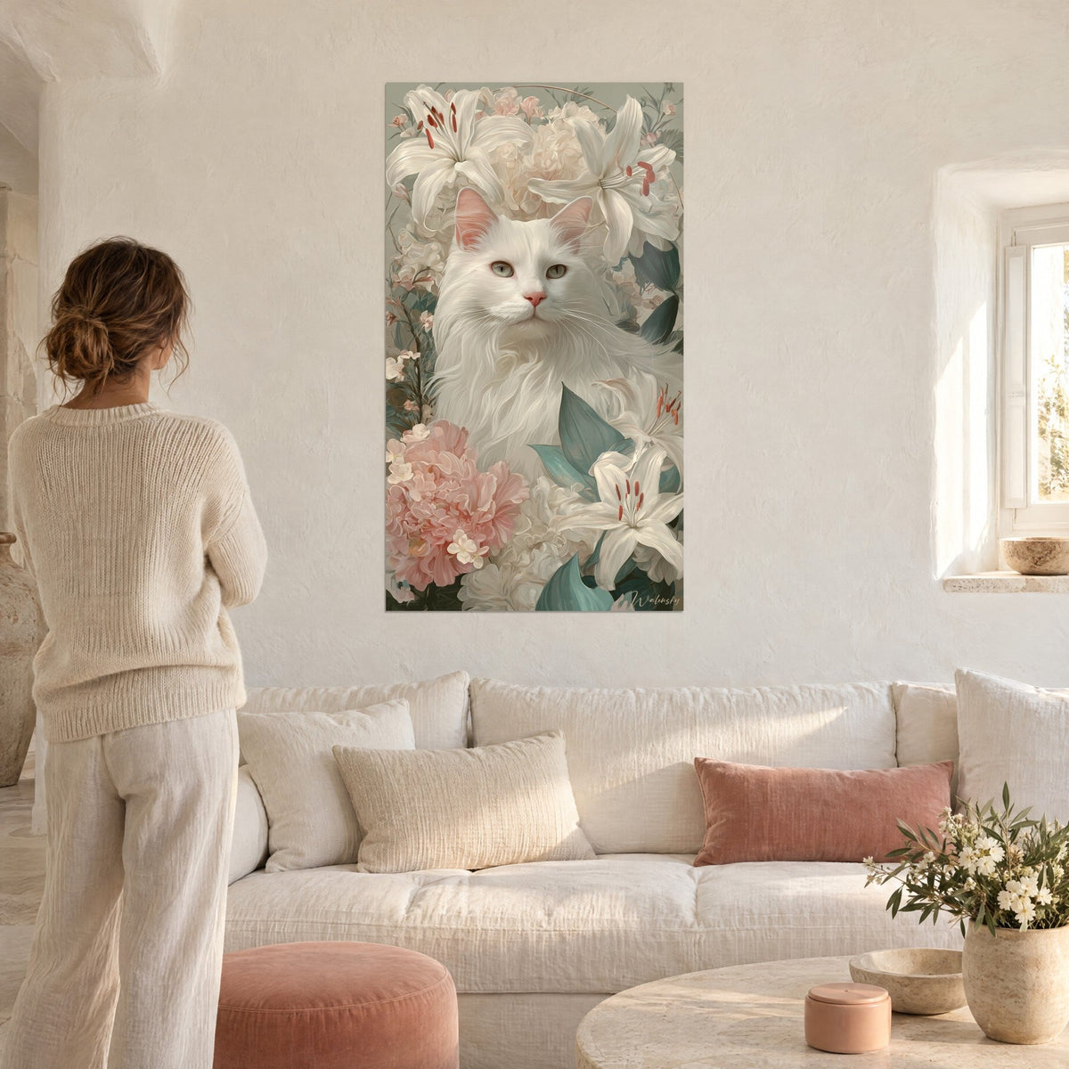 Schilderij witte Angora-kat omringd door ivoorkleurige lelies en poederroze pioenrozen, een vrouw van achteren, boven een bank in een lichte woonkamer