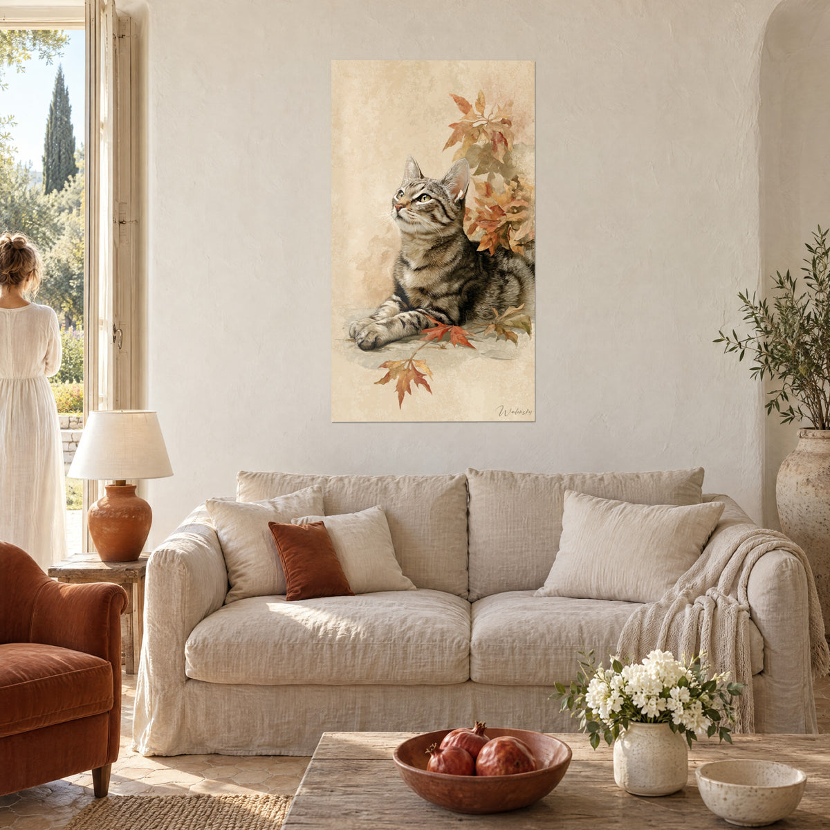 Wall art tabby cat with green eyes lifting its head, rust and beige maple leaves, above a sofa in a bright living room