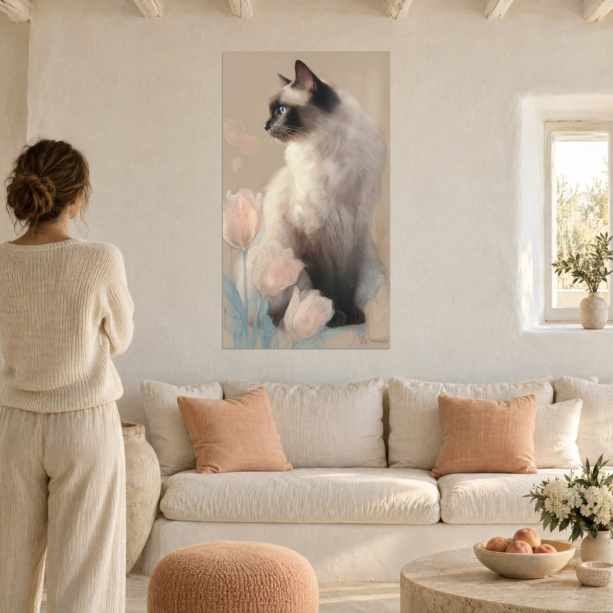 Πίνακας γάτα Birman σε προφίλ με γαλάζια μάτια, περιτριγυρισμένη από ανοιχτόροζ τουλίπες, πάνω από καναπέ σε φωτεινό σαλόνι