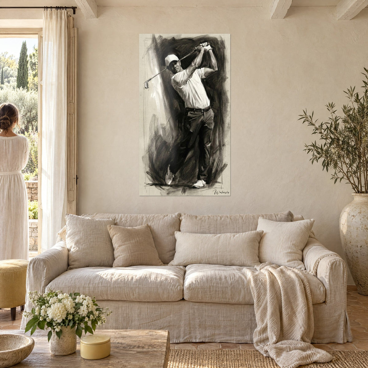 Wall art of a golfer mid-swing, white polo and black charcoal on a beige background, club raised, above the sofa in a bright living room