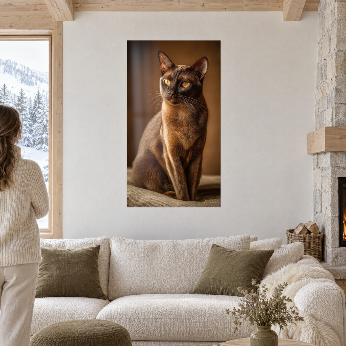 Quadro gatto birmano seduto, manto color cioccolato e occhi ambra, di fronte a una donna di spalle sopra un divano in un soggiorno luminoso