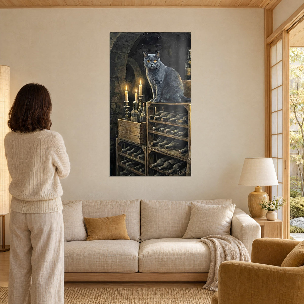 Tableau chat chartreux gris-bleu aux yeux ambrés, perché sur un casier de bouteilles, bougies dorées, au-dessus d'un canapé dans un salon lumineux