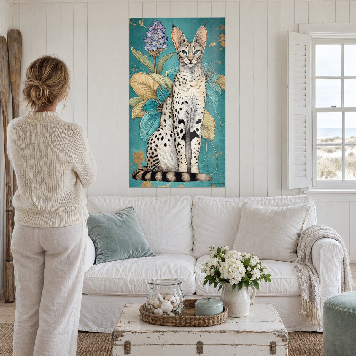Cuadro serval de ojos azules sentado entre flores turquesas y hojas doradas, fondo verde azulado, encima de un sofá en un salón luminoso