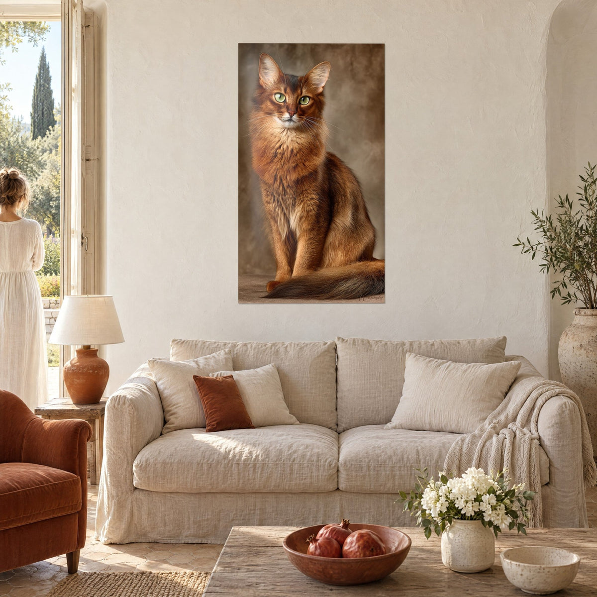 Quadro gatto Somalo rosso dagli occhi verdi, seduto, pelliccia ramata su sfondo marrone, due donne di spalle, divano di lino beige