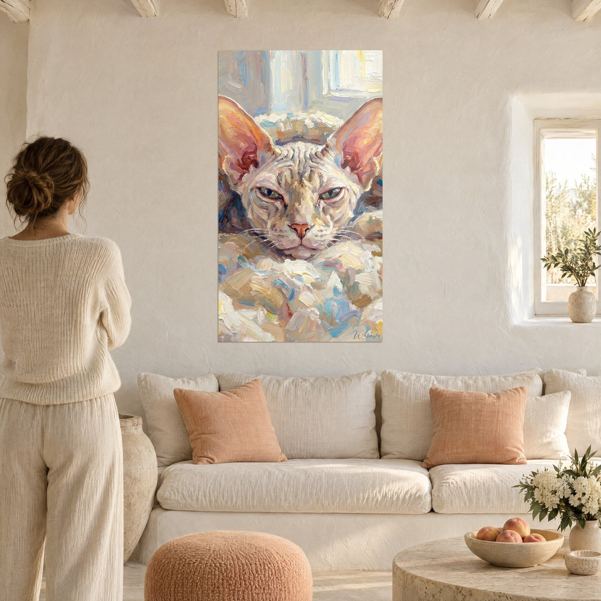 Wall art sphynx cat with large coral-pink ears, cream coat and blue brushstrokes, above a sofa in a bright living room