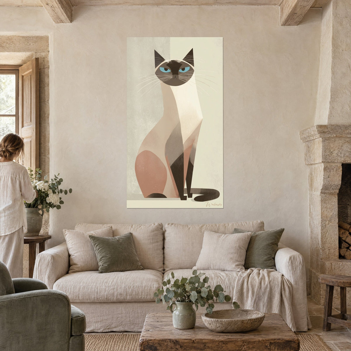Tableau chat siamois stylisé aux yeux bleus, pelage crème et ocre rosé, fond gris et ivoire, au-dessus d'un canapé dans un salon lumineux