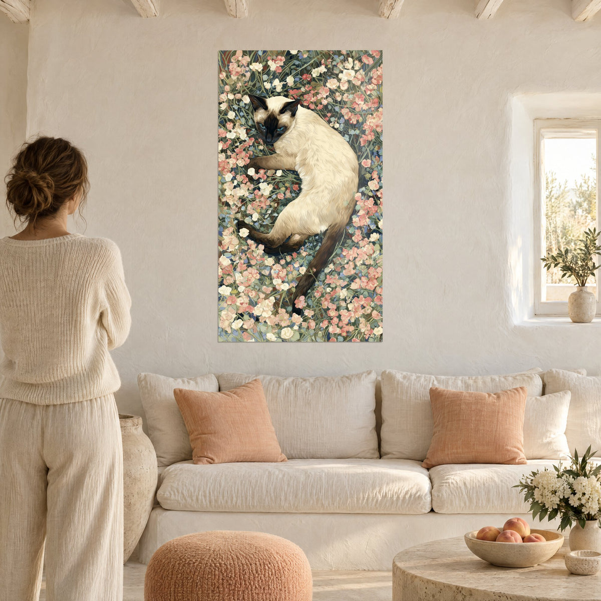 Gemälde Siamkatze liegend zwischen lachsrosa und cremefarbenen Blüten, blaue Augen, Frau von hinten über einem Sofa in einem hellen Wohnzimmer