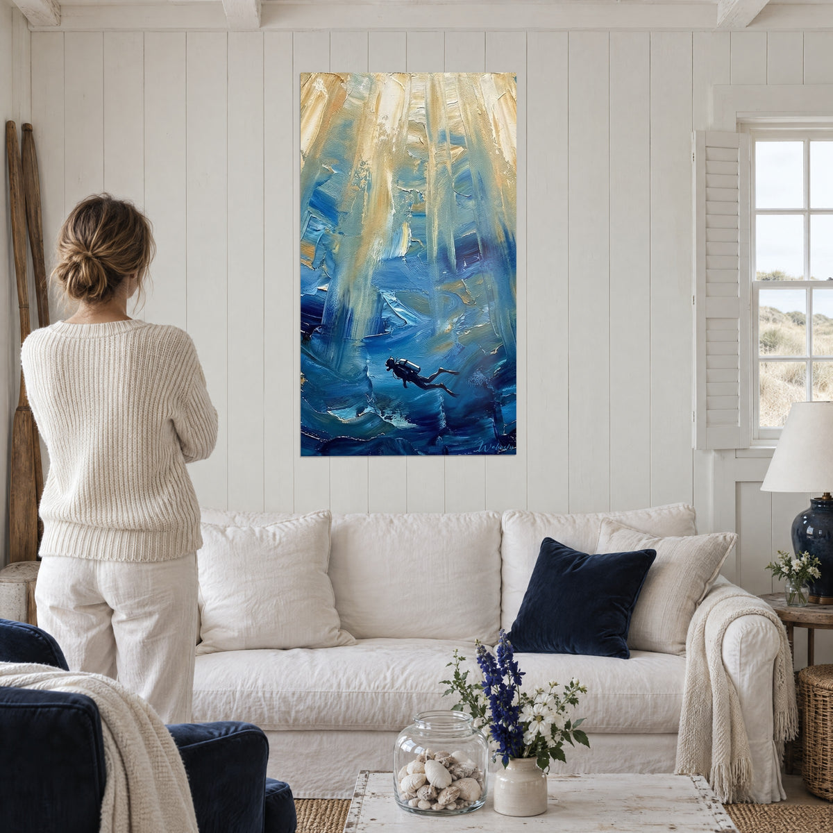 Tableau plongeur en combinaison noire dans une cavité glacée, ocre et bleu cobalt, au-dessus d'un canapé dans un salon lumineux